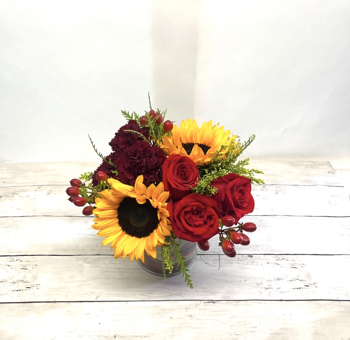 Bouquet of red roses and yellow sunflowers in a glass vase