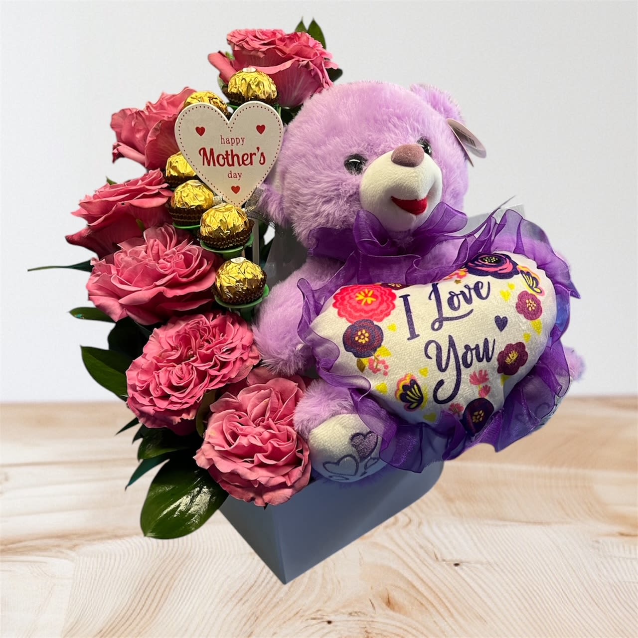 Pink roses with a purple teddy bear and chocolates in a gift box