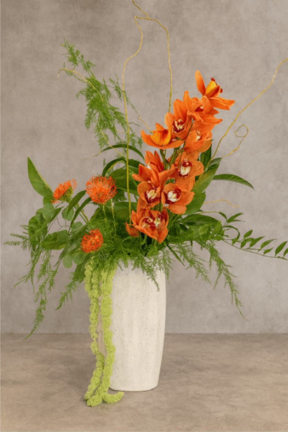 Eden - Eden is a premium floral arrangement featuring tropical blooms and bold botanical textures - crafted to last and structured to elevate. With orchids, amaranthus, tropical blooms, and dramatic greenery, it brings depth, movement, and presence to entryways, reception desks, conference rooms, and hospitality spaces.  Built for longevity, this arrangement is also part of our subscription offering for businesses and individuals seeking fresh, impactful florals with a longer shelf life and consistent service.  Colors and ingredients vary with seasonal availability, but the tropical tone and sculptural elegance remain.