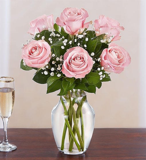 Pink roses arranged in a clear glass vase with baby's breath