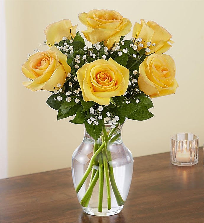 Yellow roses arranged in a clear glass vase with baby's breath
