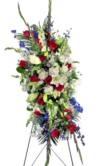 Tall standing floral spray with red roses, white lilies, and blue accents
