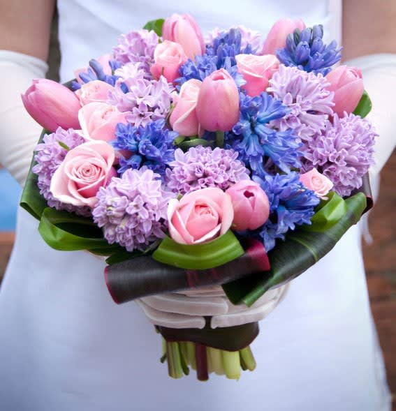 Pink tulips and roses with purple and blue flowers in a hand-tied bouquet
