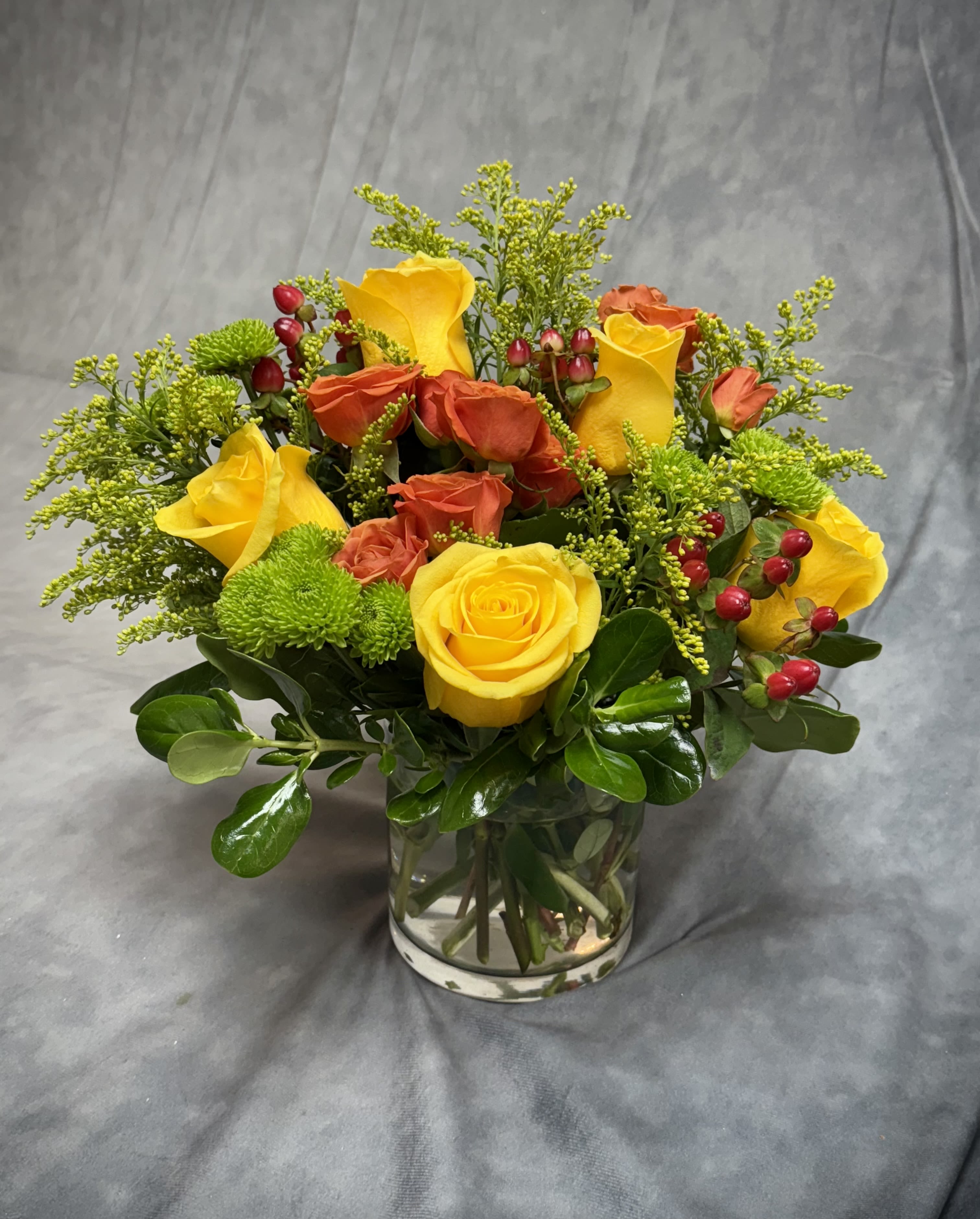 Yellow and orange roses arranged in a clear glass vase