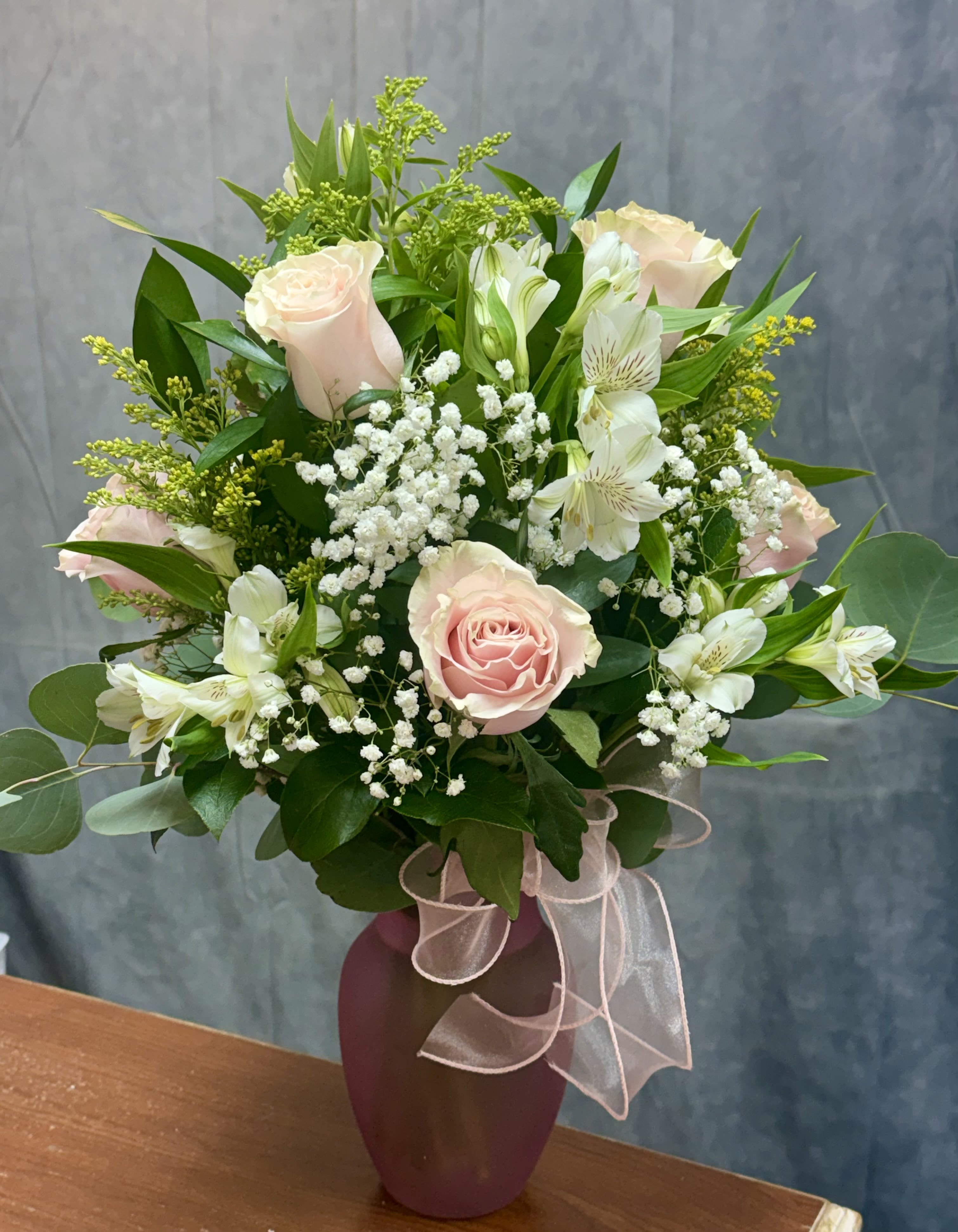 Pink roses and white blooms in a pink frosted vase with a sheer ribbon bow