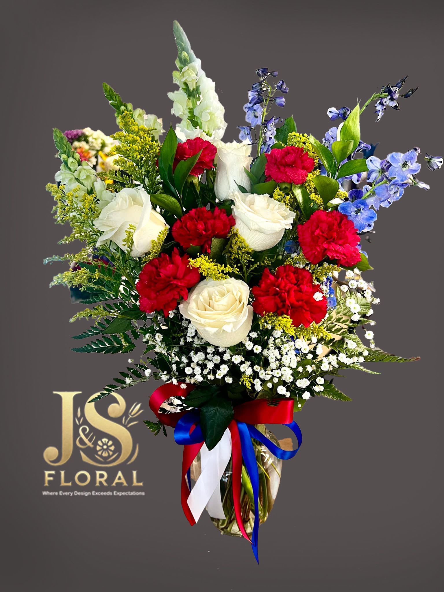 Bouquet of red and white roses with blue flowers in a glass vase