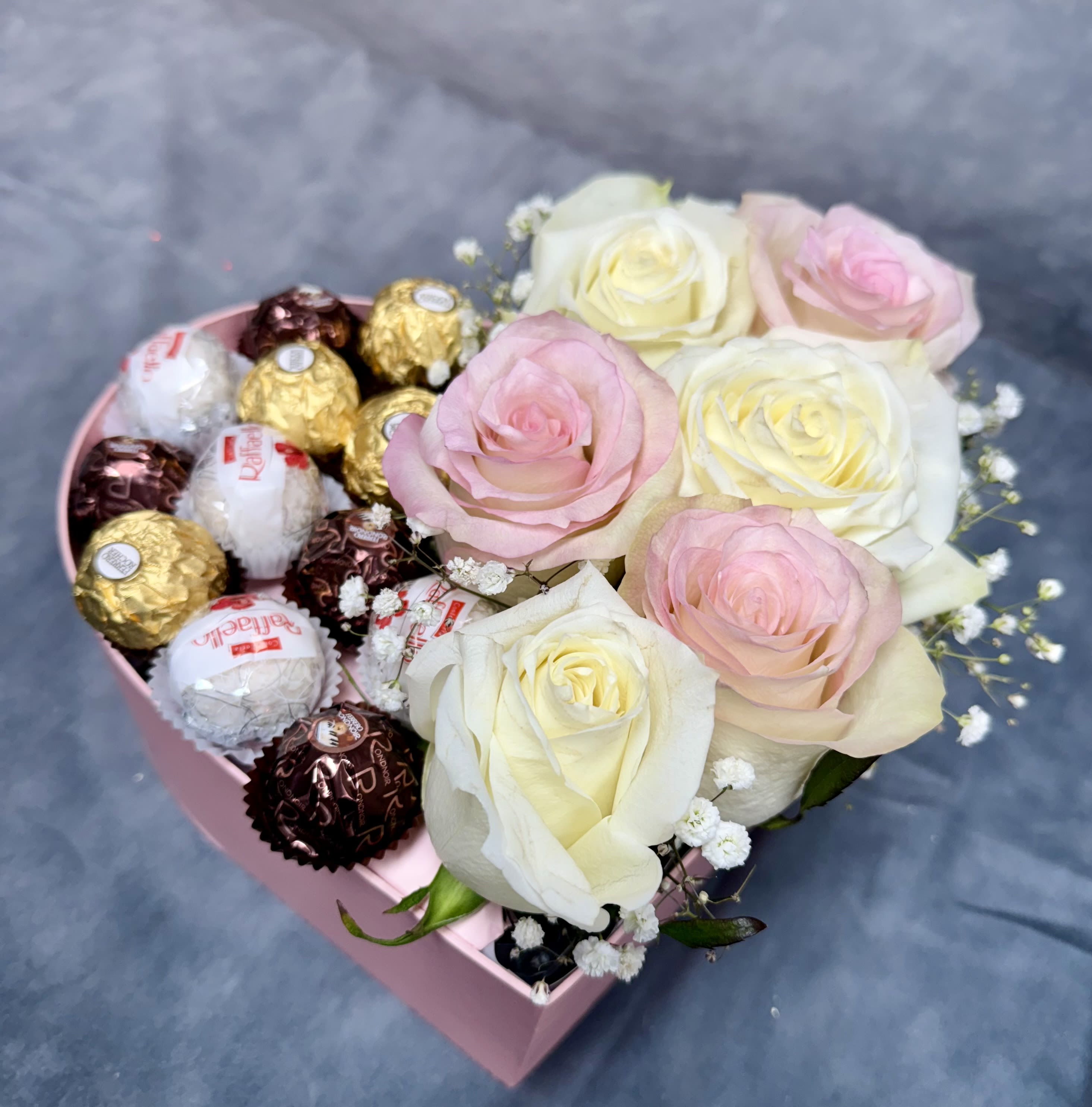 Pink heart-shaped box with roses and assorted chocolates