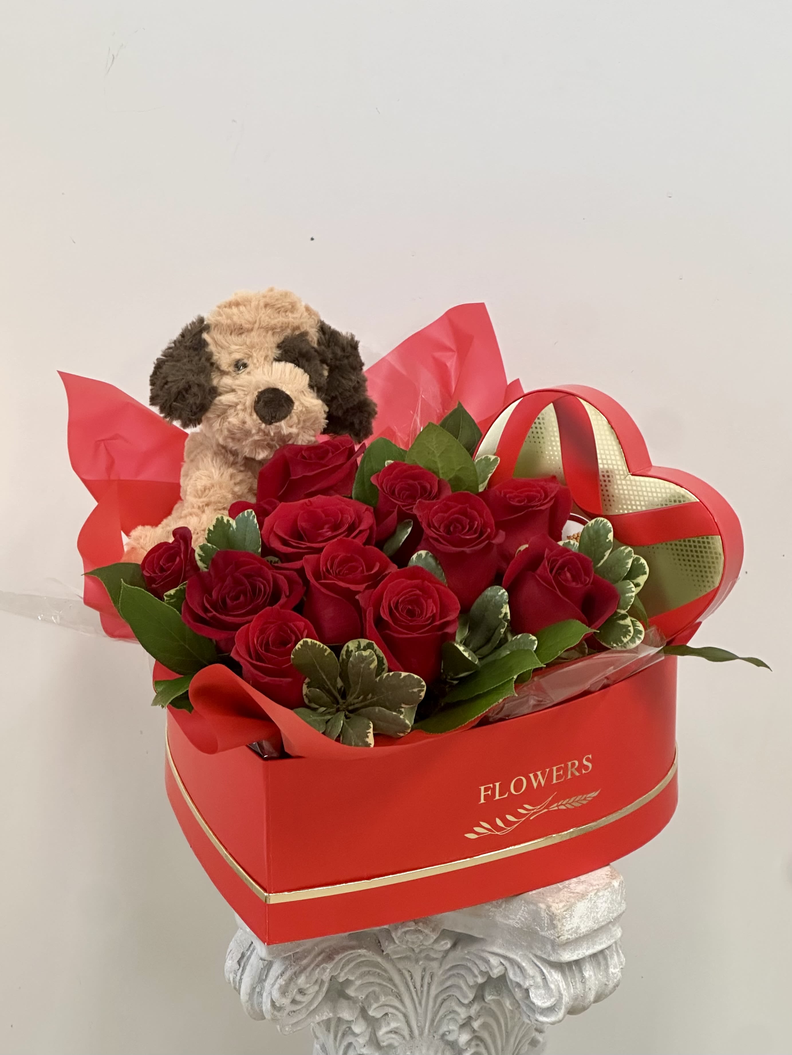 Red roses in a heart-shaped box with a plush dog