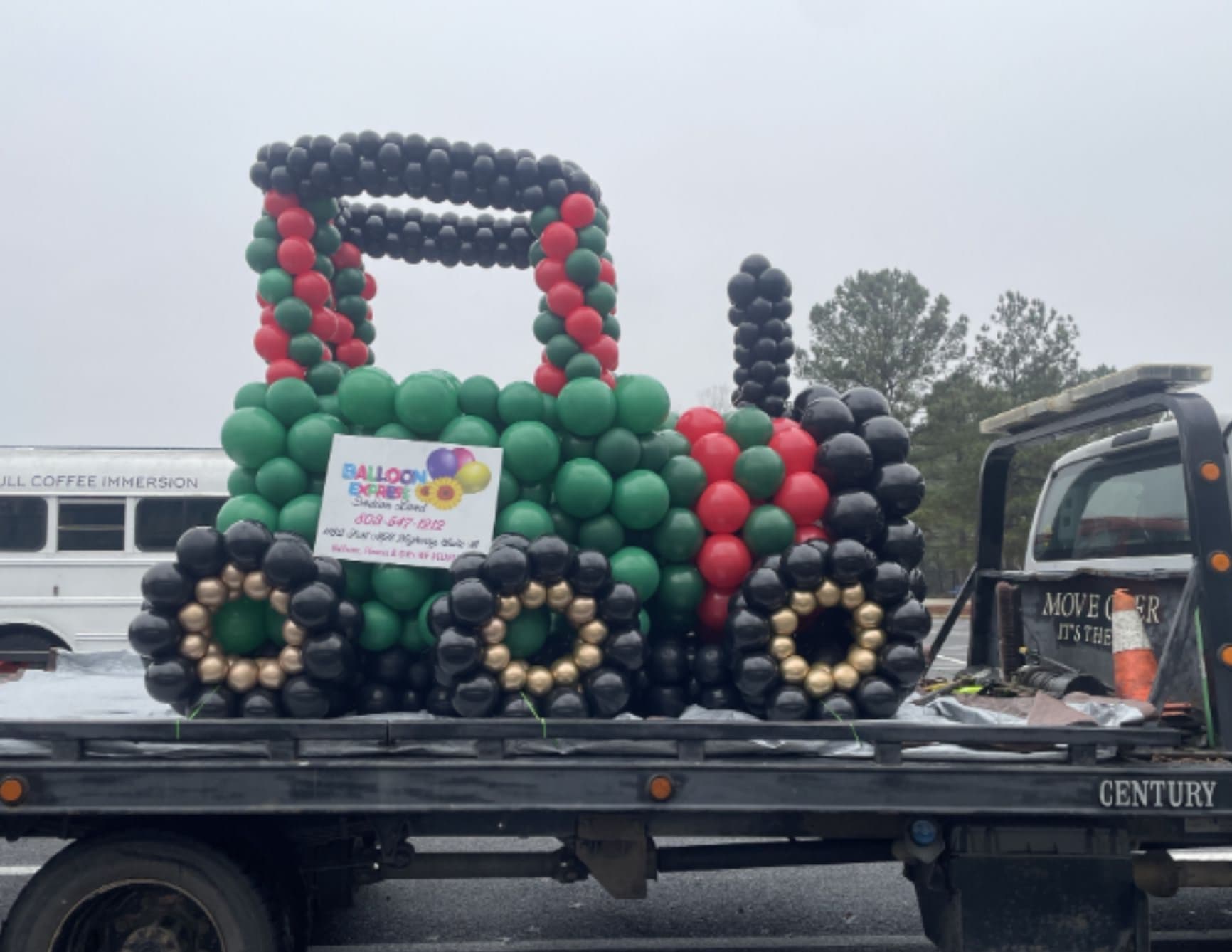 Balloon display shaped like a tractor on a flatbed truck