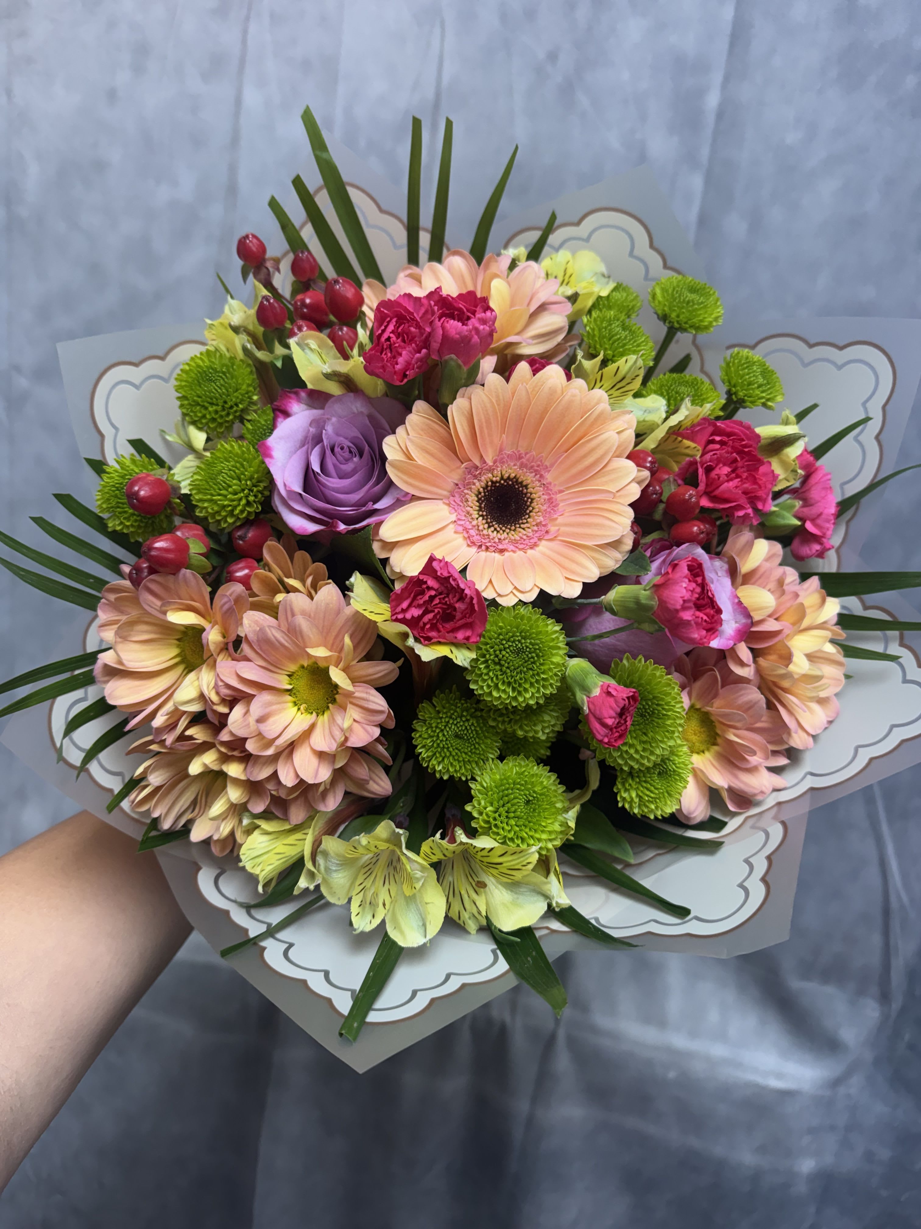Peach Blossom Bouquet  - A charming blend of peach, lavender, pink, and green blooms arranged into a lush hand-tied bouquet. Featuring gerbera daisies, roses, carnations, chrysanthemums, alstroemeria, and fresh greenery, this design is perfect for birthdays, anniversaries, congratulations, or just because.