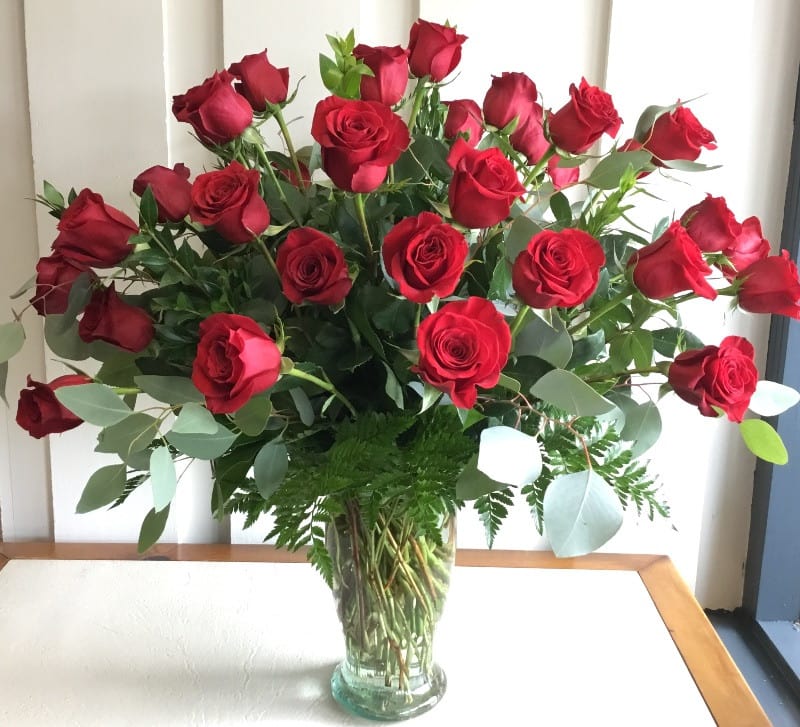 A large bouquet of red roses in a clear glass vase