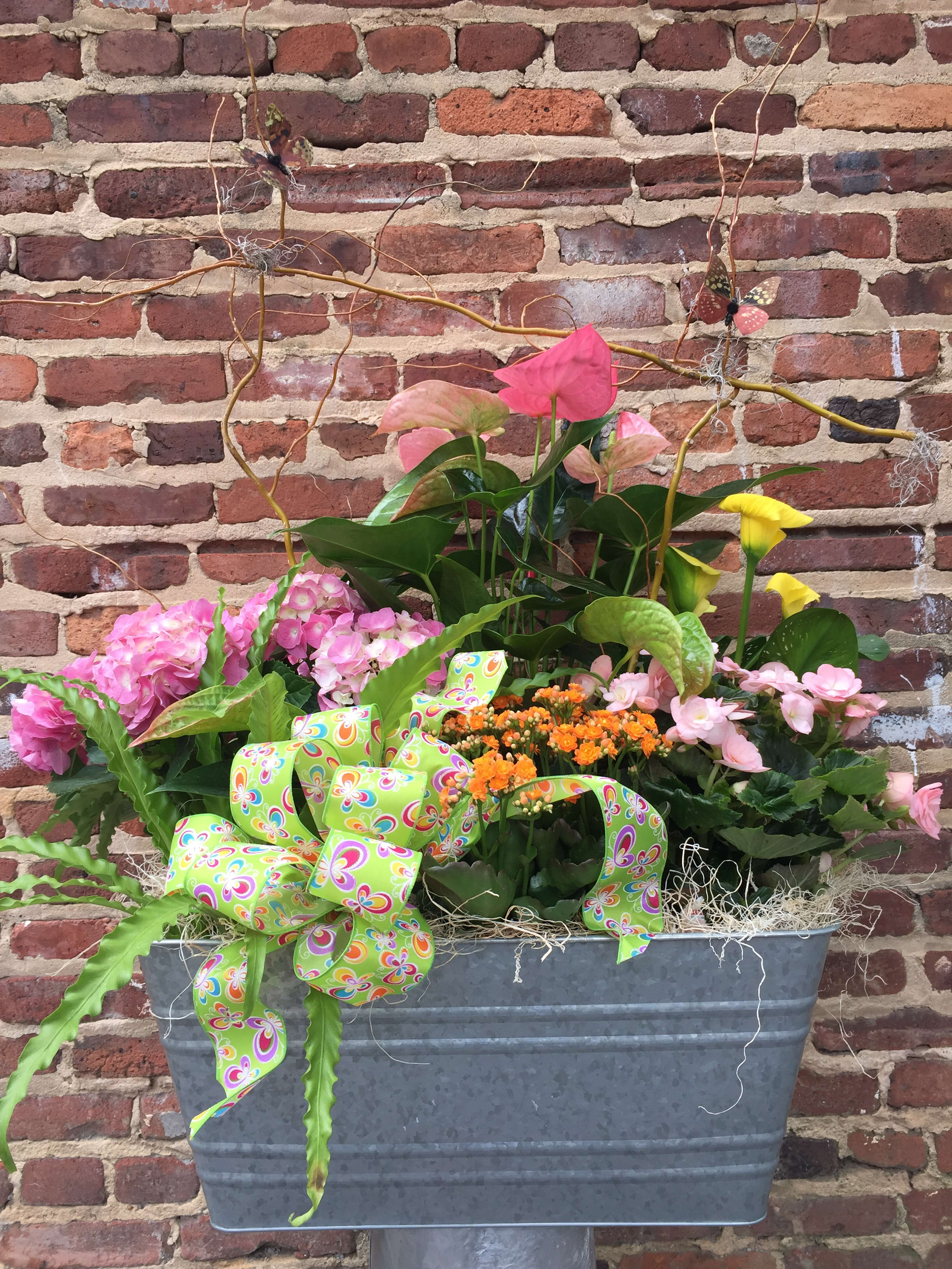 Mixed floral planter with pink hydrangeas, anthuriums, and yellow calla lilies in a metal container