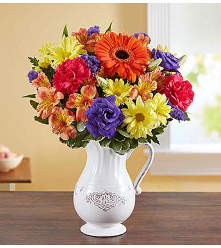 Colorful bouquet of mixed flowers in a white pitcher vase