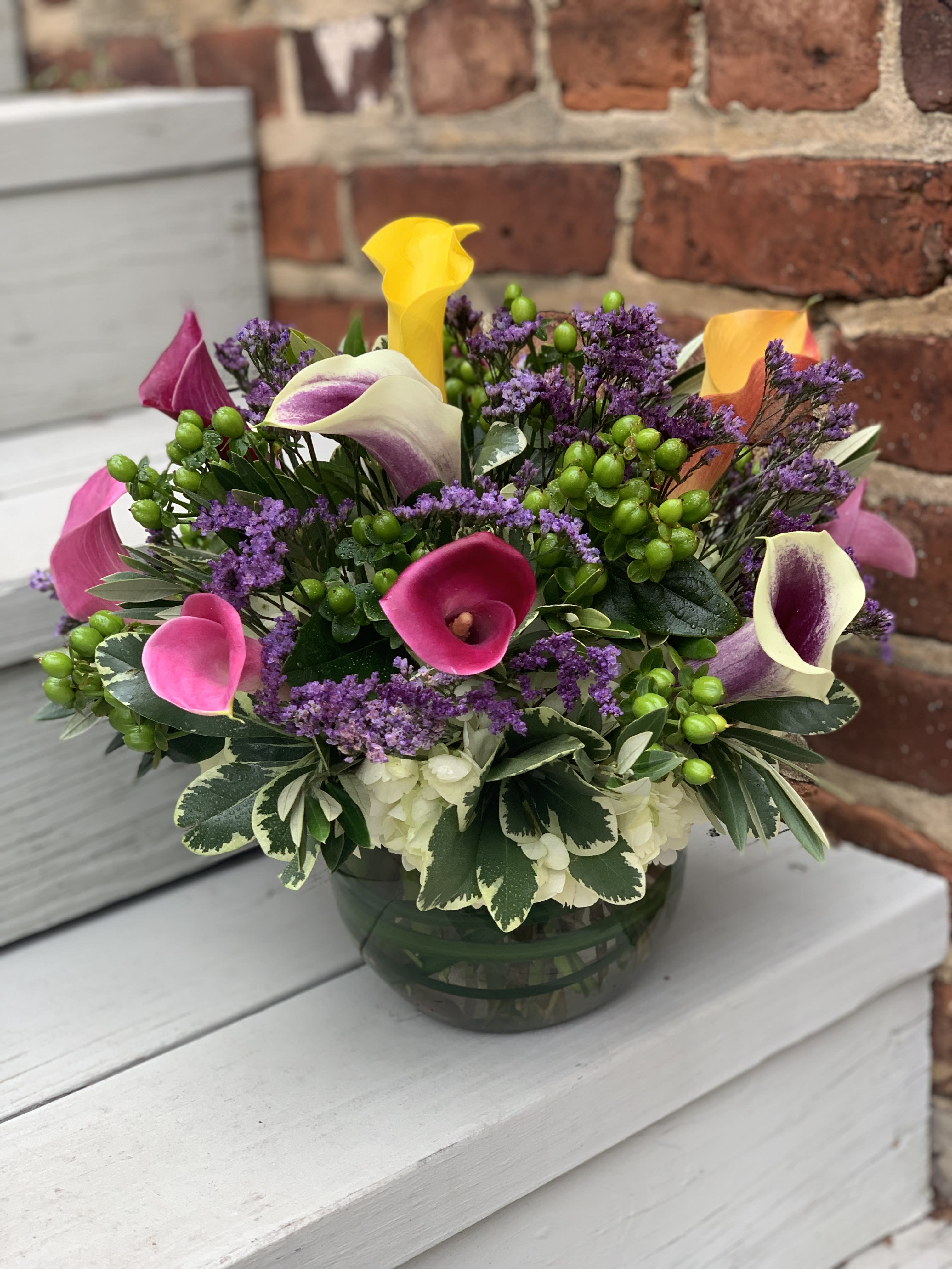 Mixed calla lily arrangement in a glass bowl vase