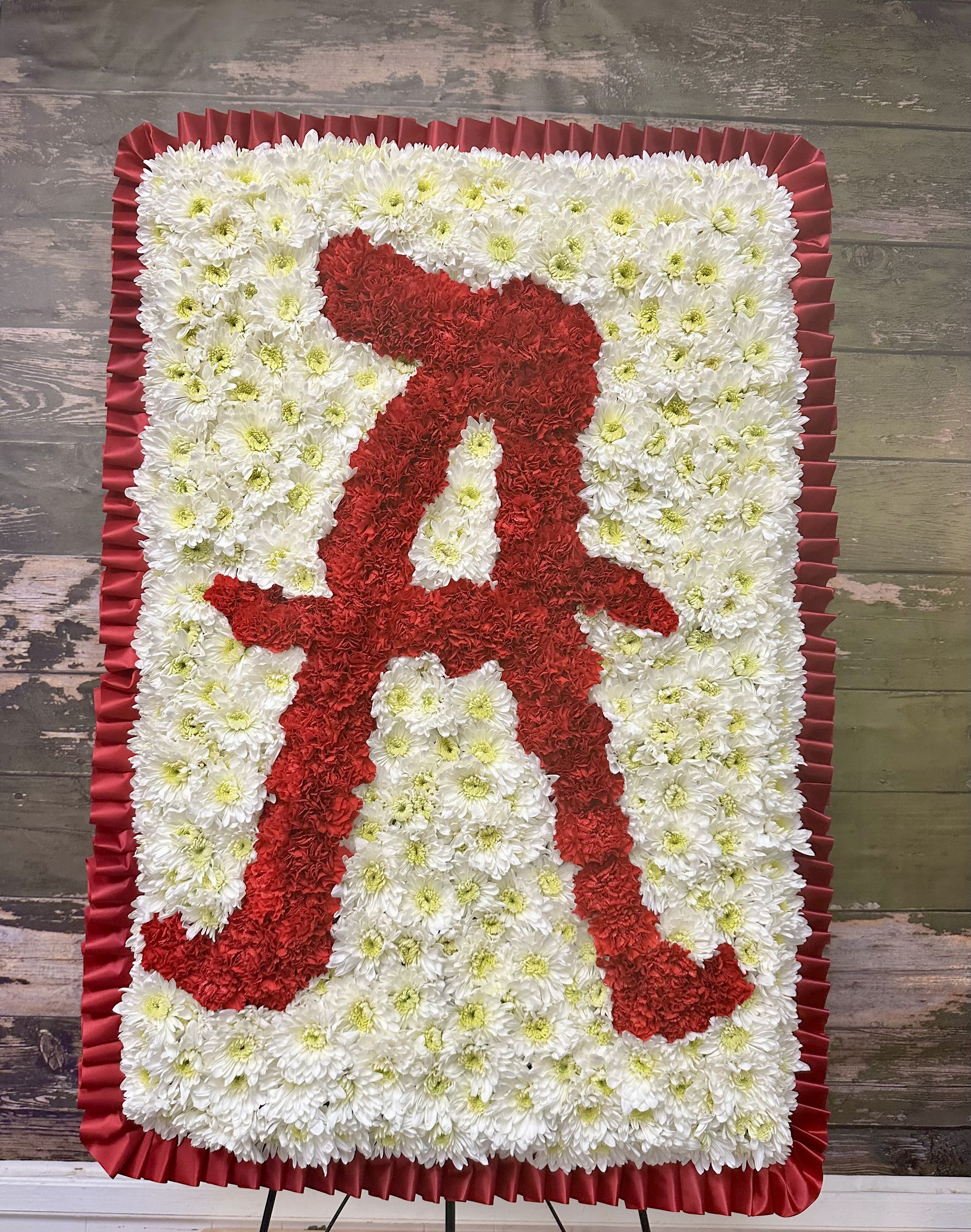 Red and white floral standing tribute with a ribbon border