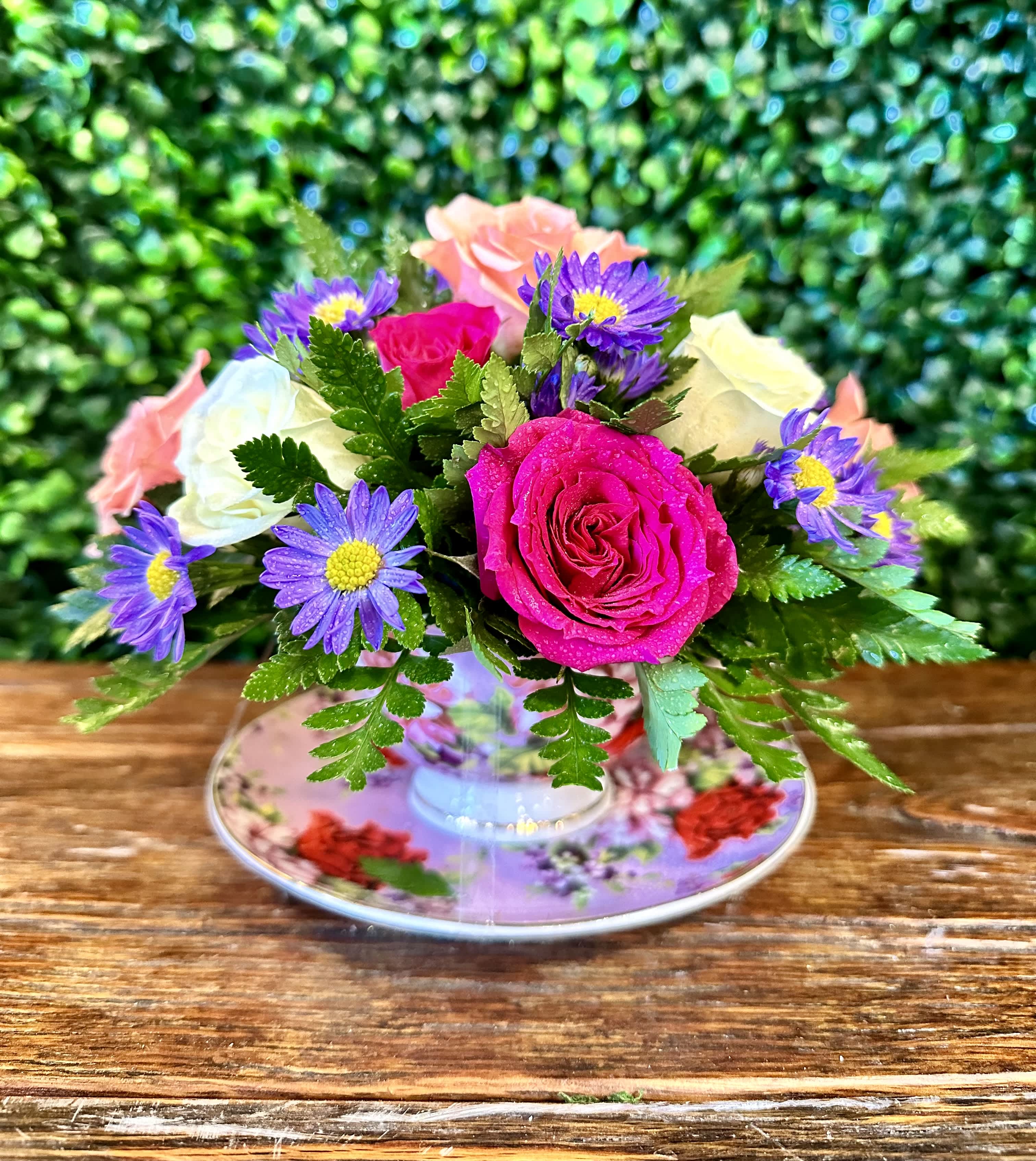 Bouquet of pink and white roses with purple daisy-like flowers in a floral teacup
