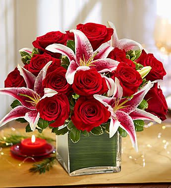 Red roses and pink lilies arranged in a square glass vase
