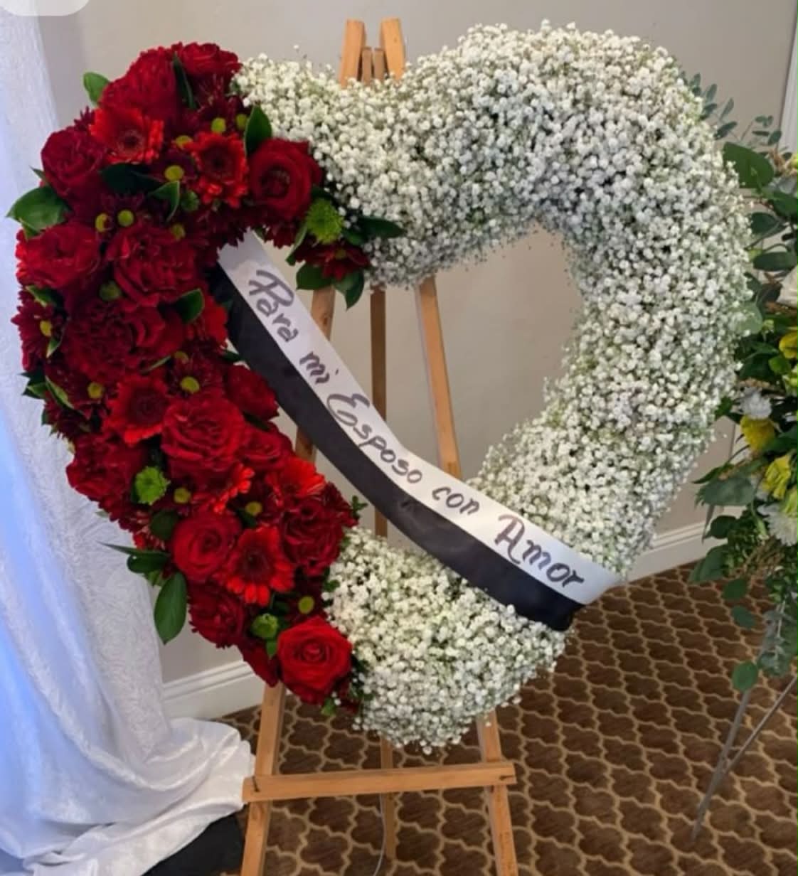 Funeral Red Heart Stand  - A heart-shaped arrangement combining rich red blooms with soft white baby’s breath — symbolizing love, peace, and remembrance. The ribbon can be personalized with your own message to honor your loved one.