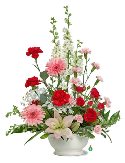 Pink and red mixed flower arrangement in a white bowl vase