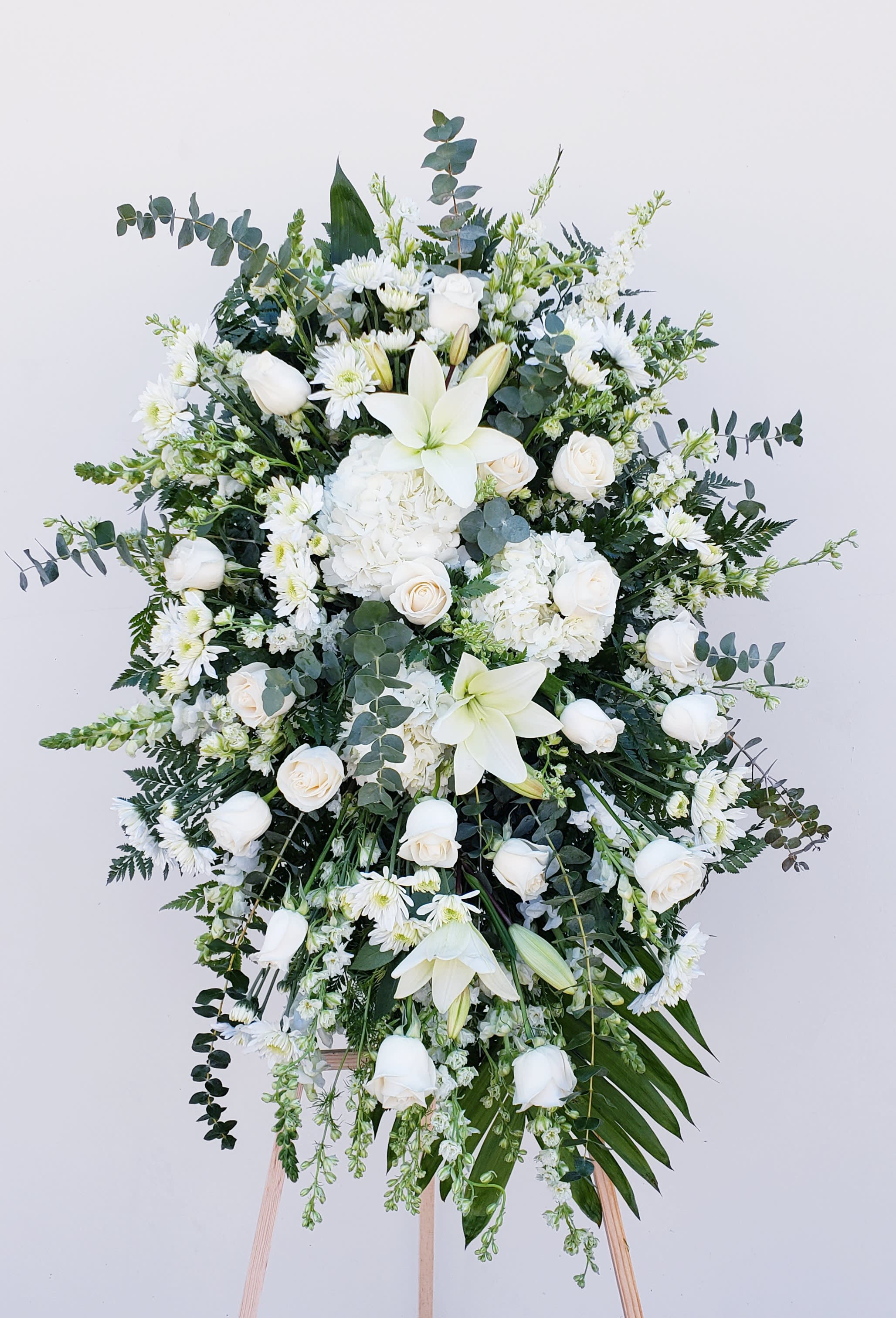 Large white floral standing spray with lilies, roses, and daisies