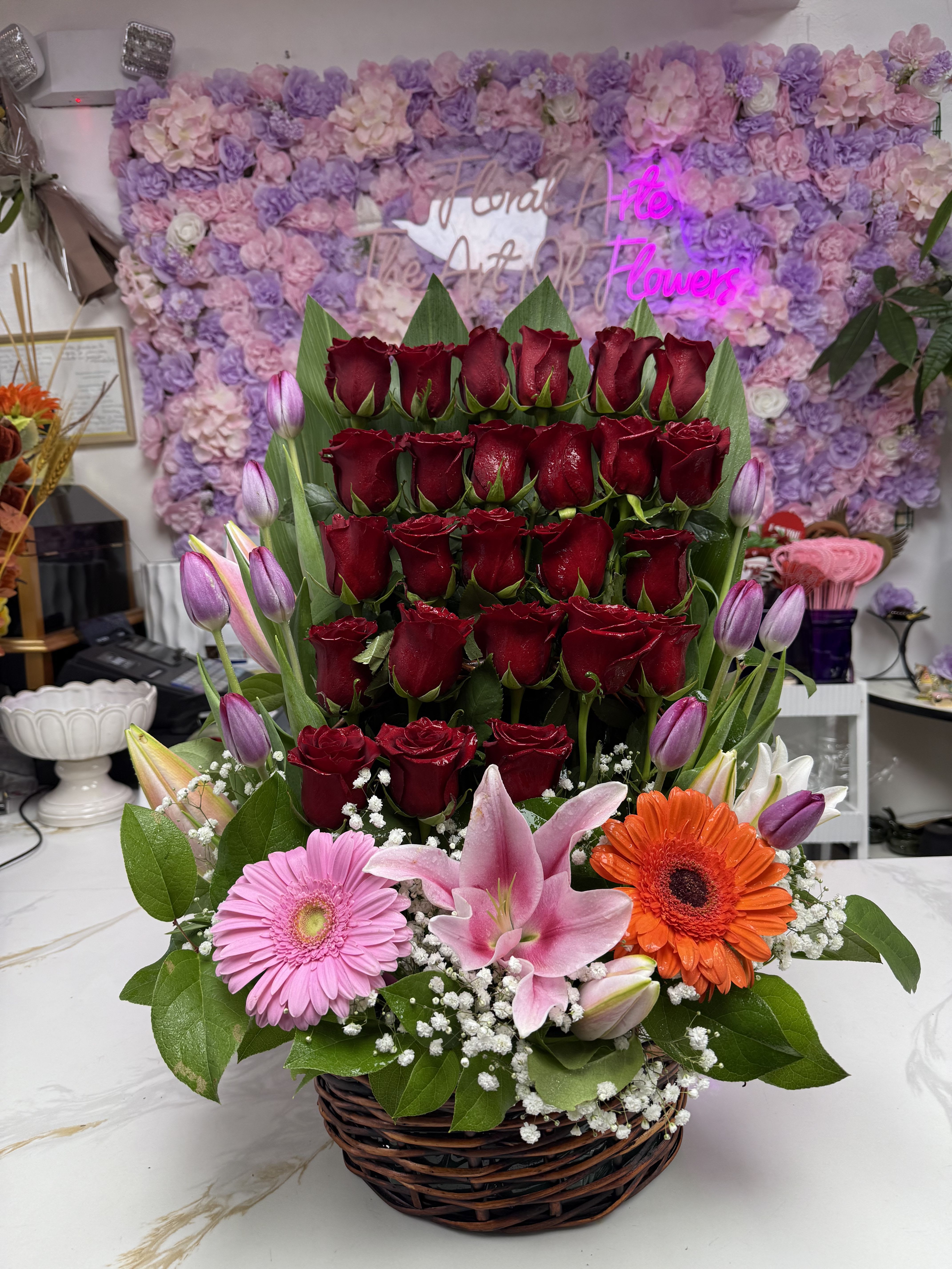 Basket arrangement of red roses with pink lilies and gerbera daisies