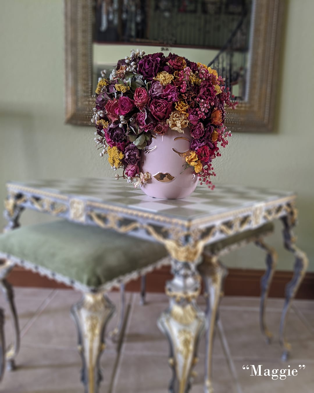 Pink vase with a dense arrangement of dried flowers and berries
