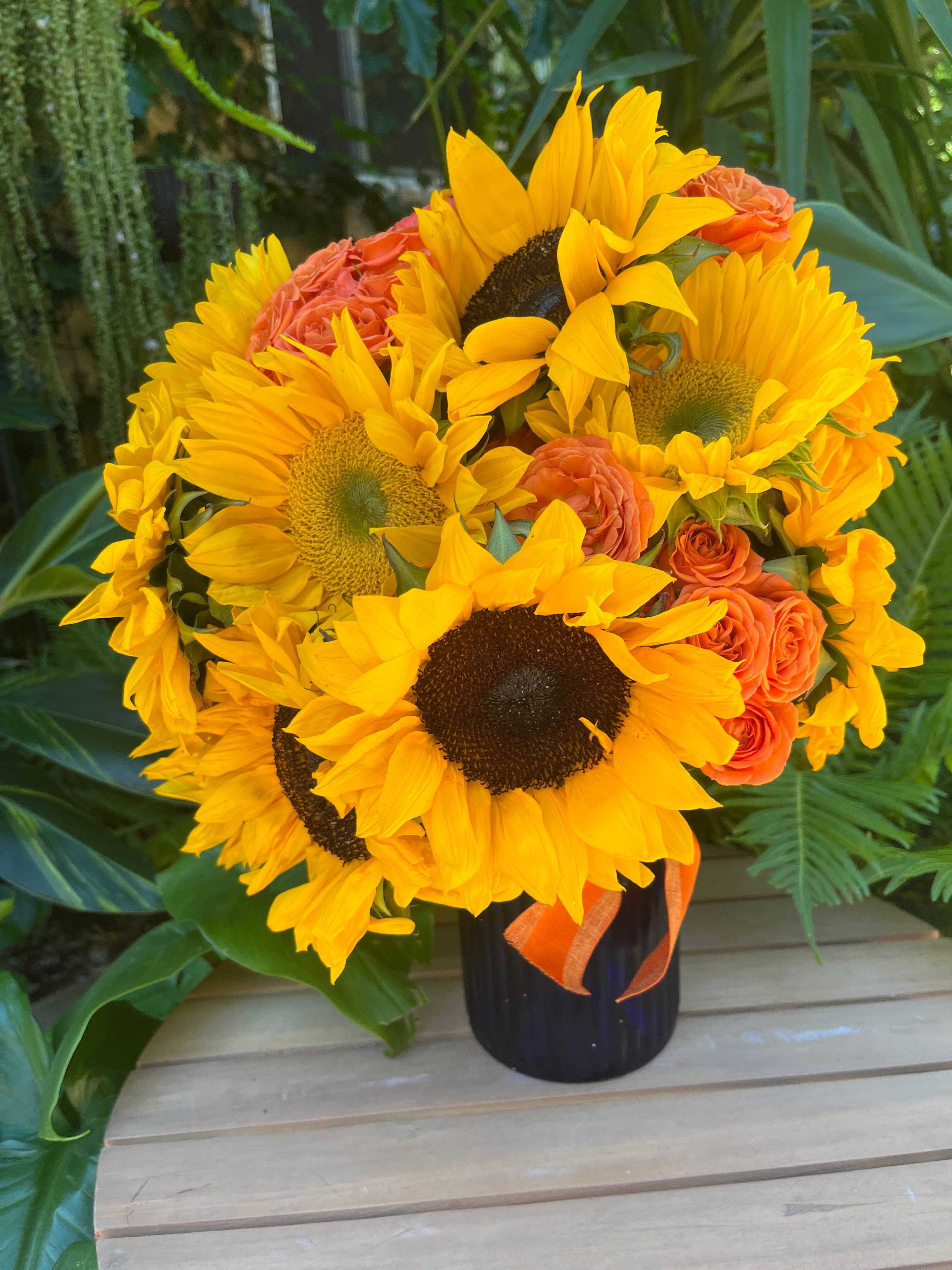 Sunflower and orange rose bouquet in a black vase