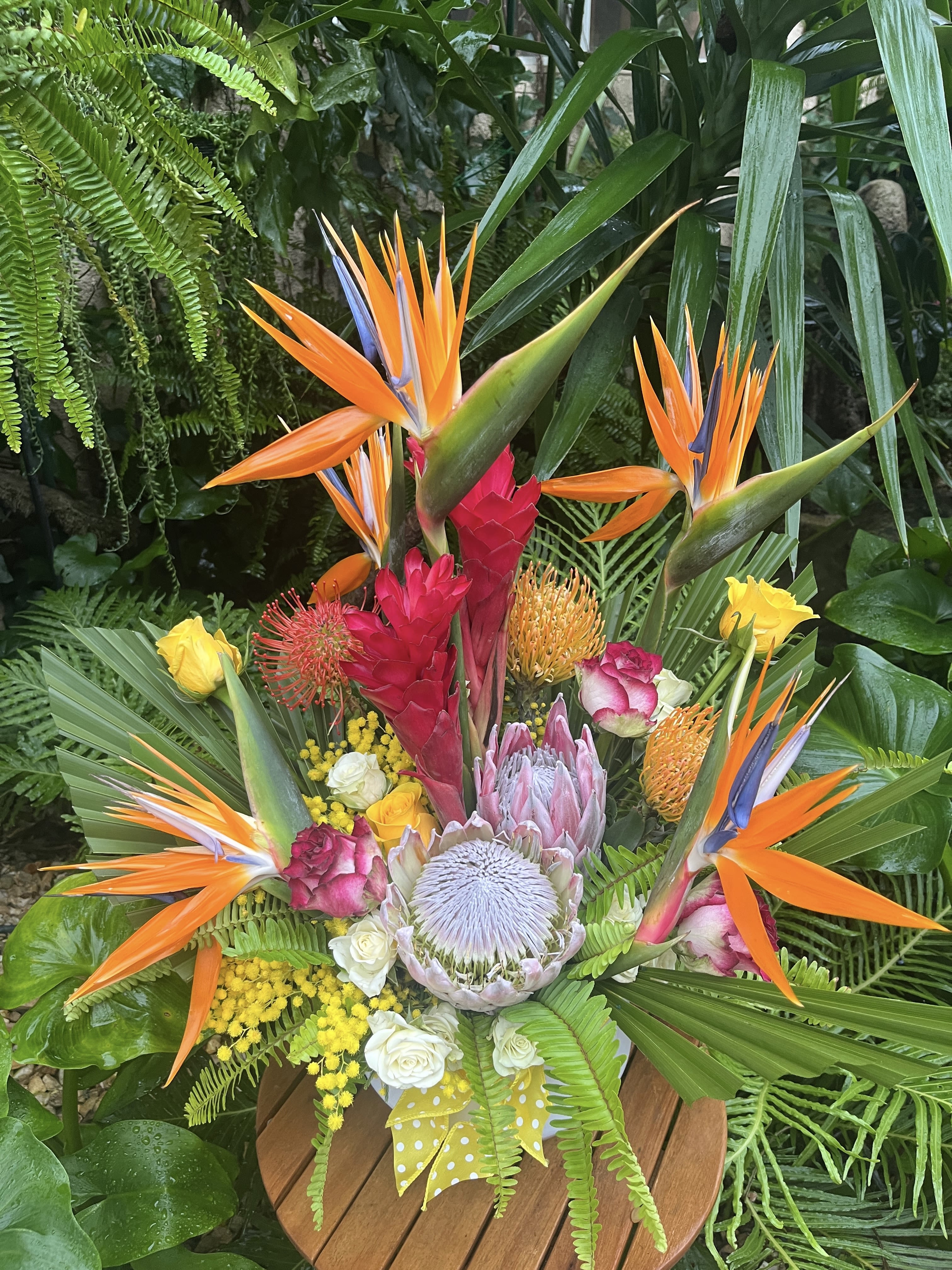 Tropical bouquet with orange bird-of-paradise and pink protea in a vase
