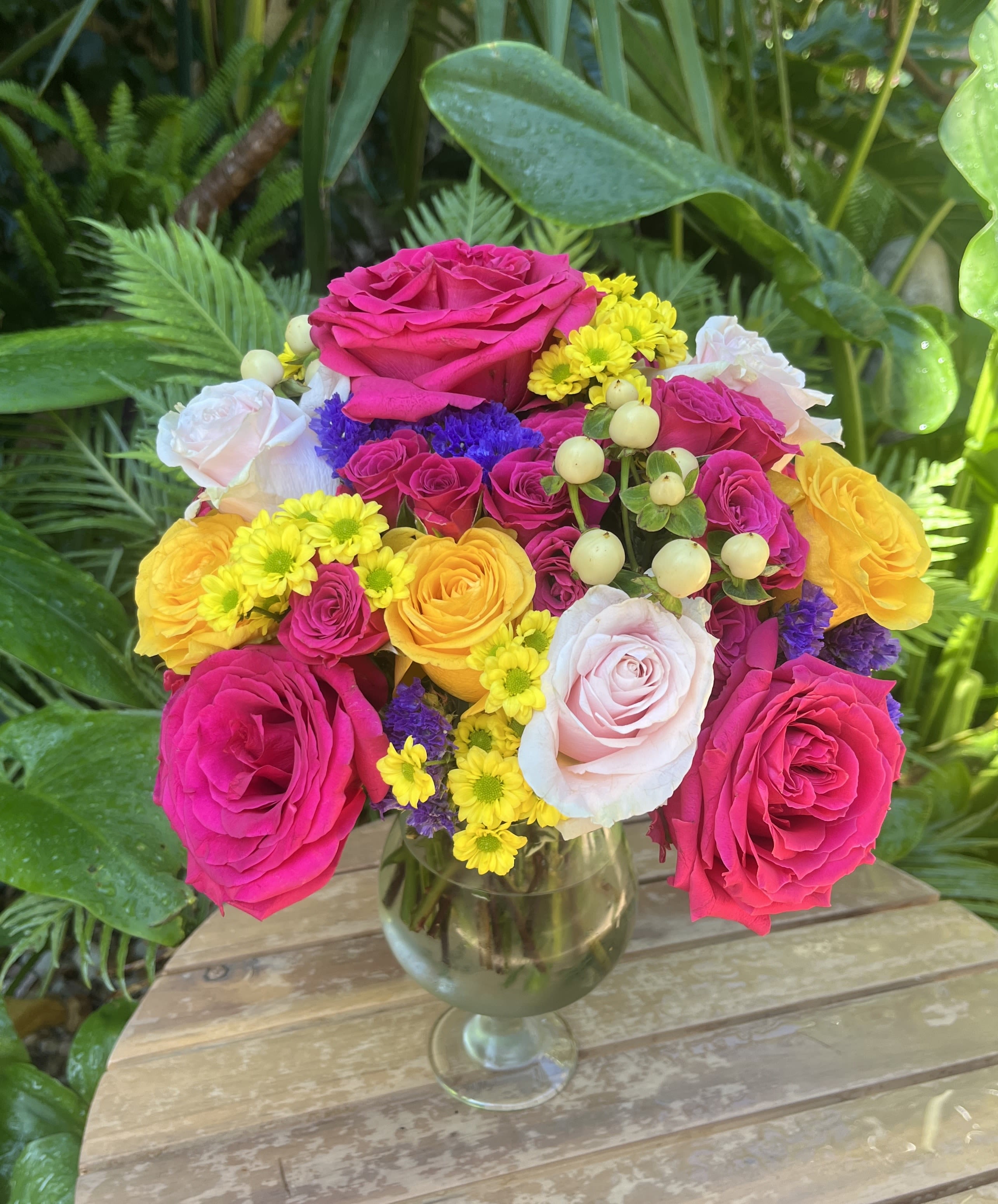 Mixed bouquet of pink, yellow, and white roses in a glass vase