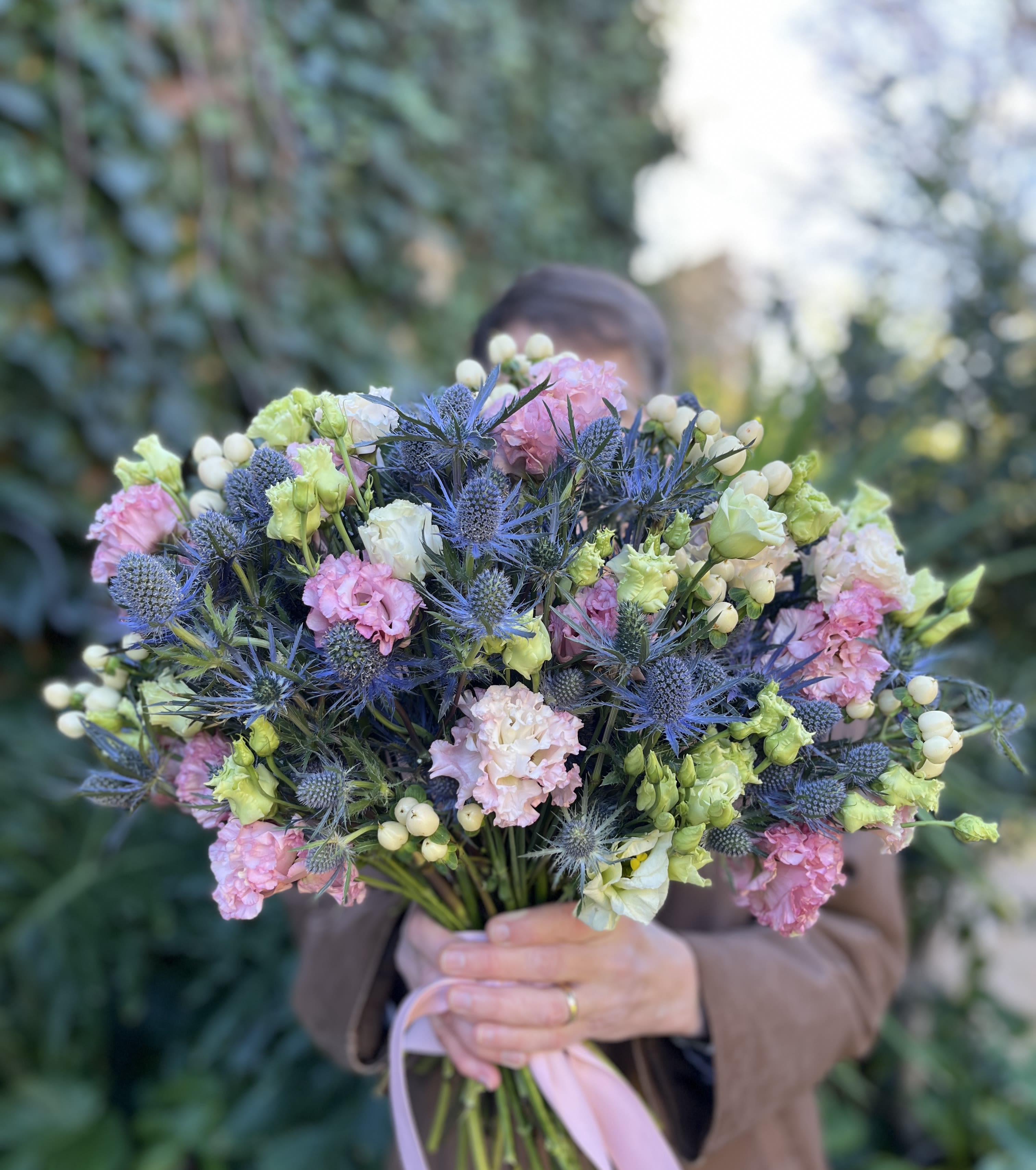 Handheld bouquet of pink, white, and blue flowers tied with a ribbon