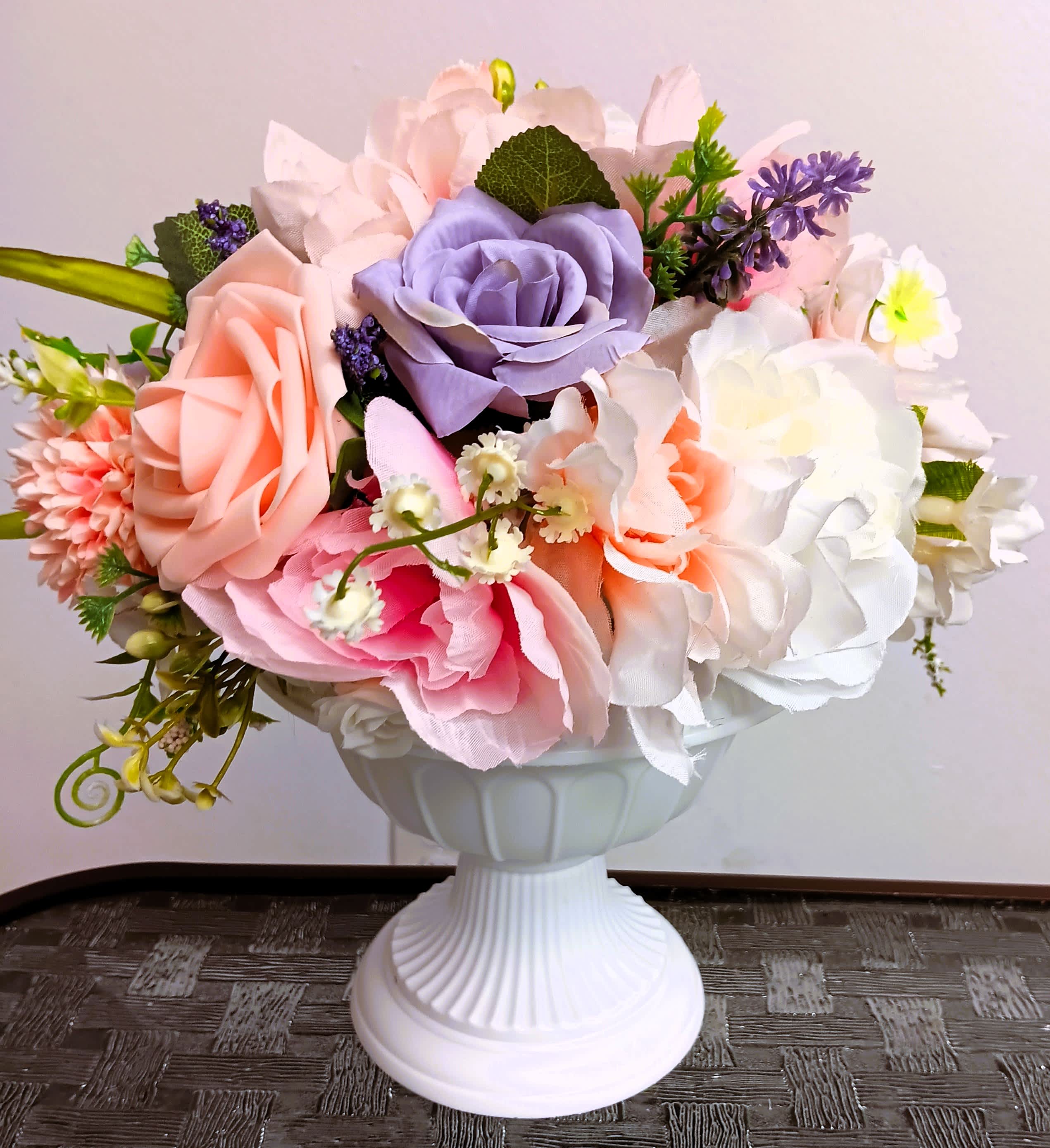 Artificial pastel rose bouquet in a white pedestal vase