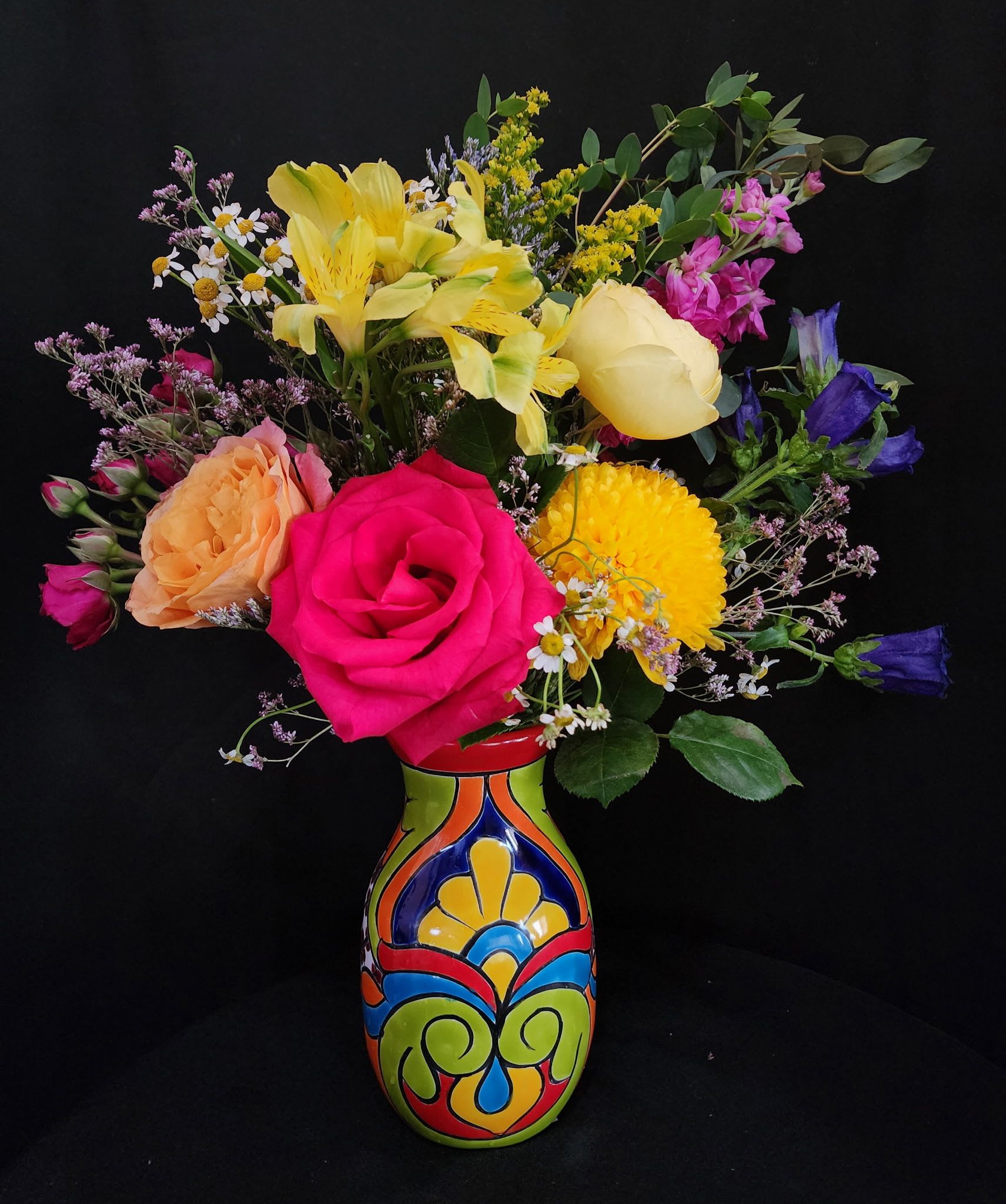 Mexican Paradise ***1 limited vase*** - This arrangement represents the beautiful flower colors of Mexican culture and traditions, the perfect housewarming gift for any occasion. This beautiful arrangement contains roses, mums, alstroemeria, spring roses, campanulas, stock, solidago, chamomile, limonium flowers.  Original ceramic talavera from Puebla available in limited supply.   Arrangement dimensions are approximately 18" Height x 13" Width and vase is 8" tall. 