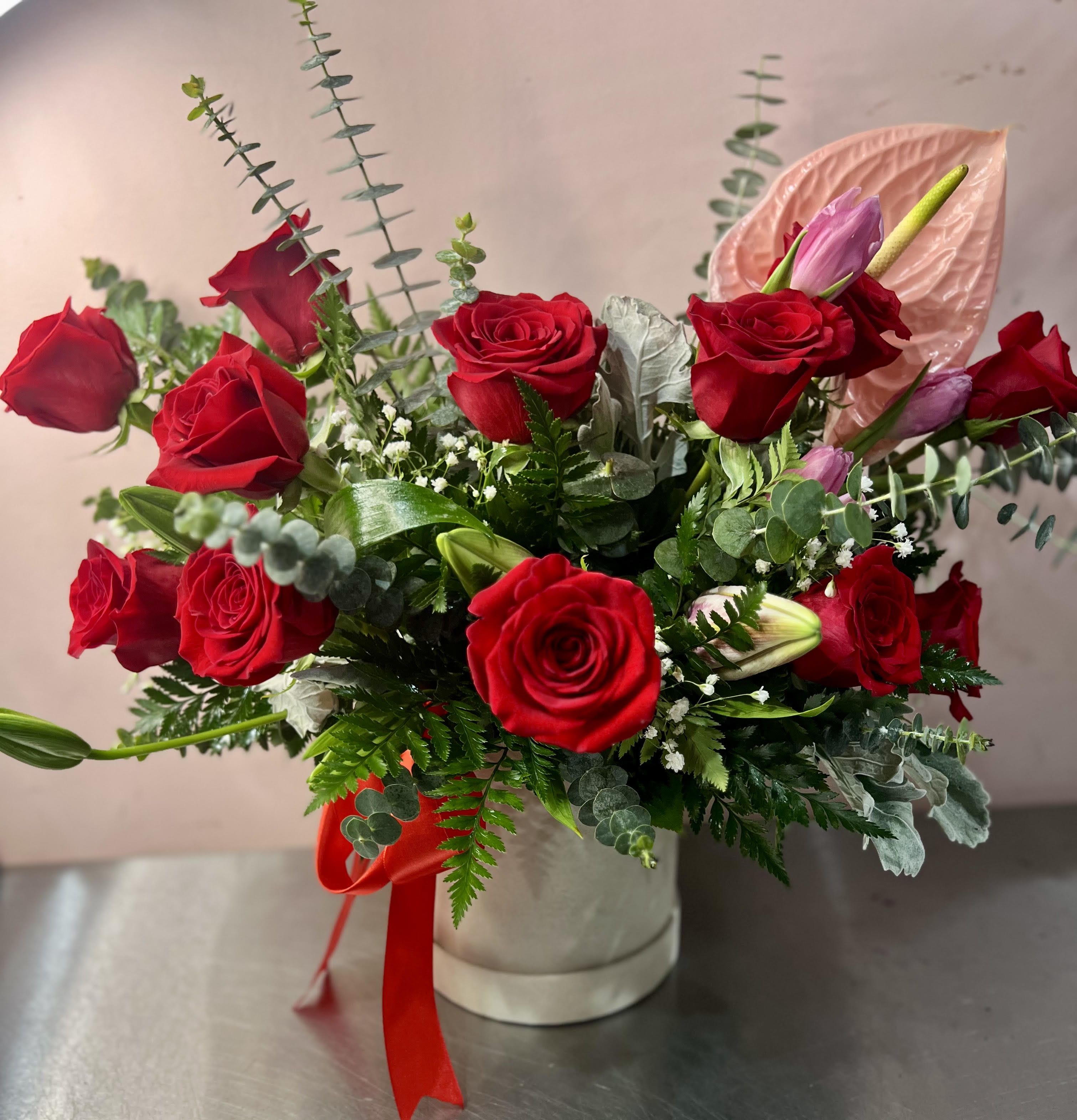 Red roses and pink lilies in a white hat box with a red ribbon