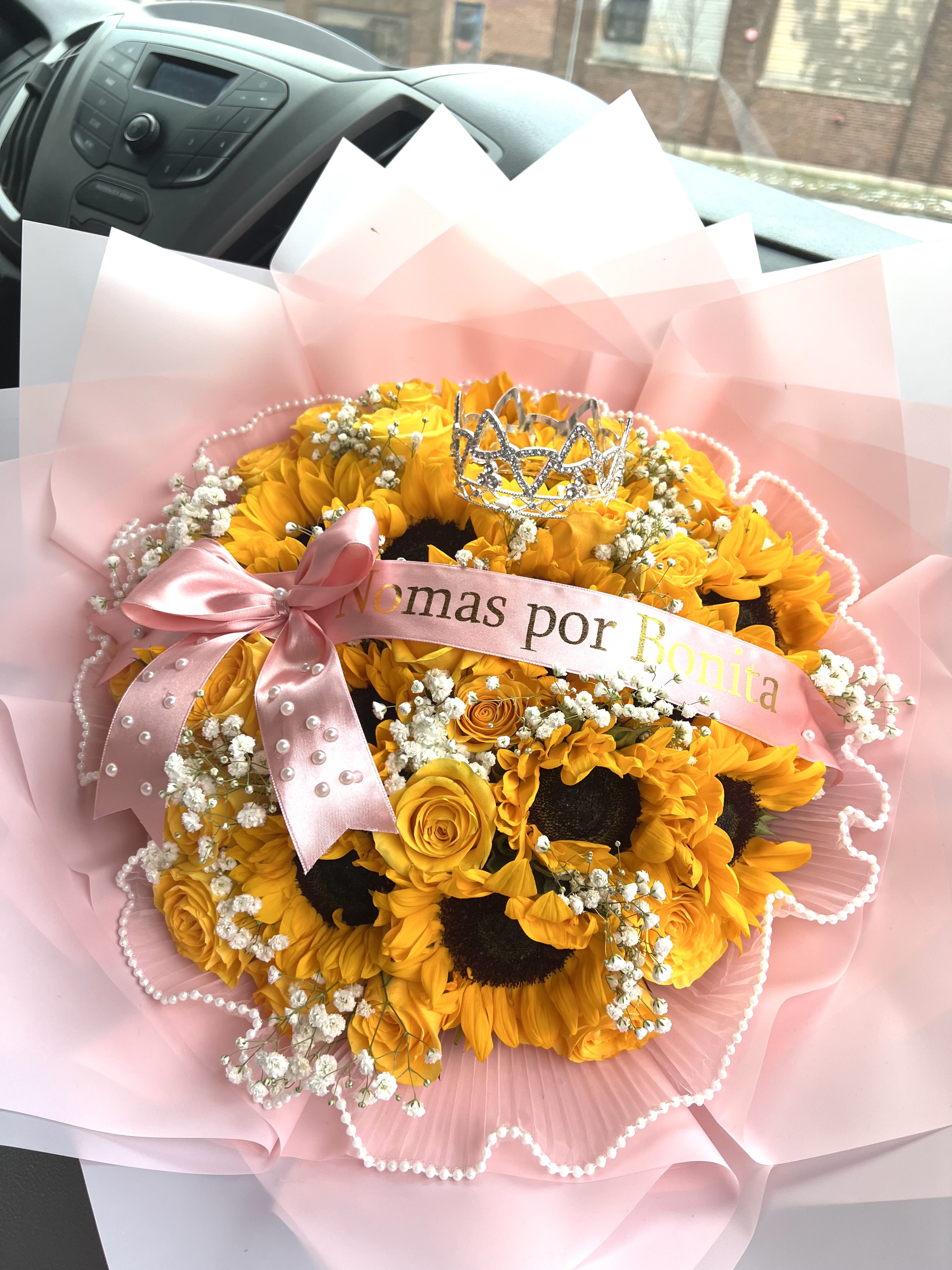Bouquet of yellow sunflowers and roses with a pink ribbon and tiara