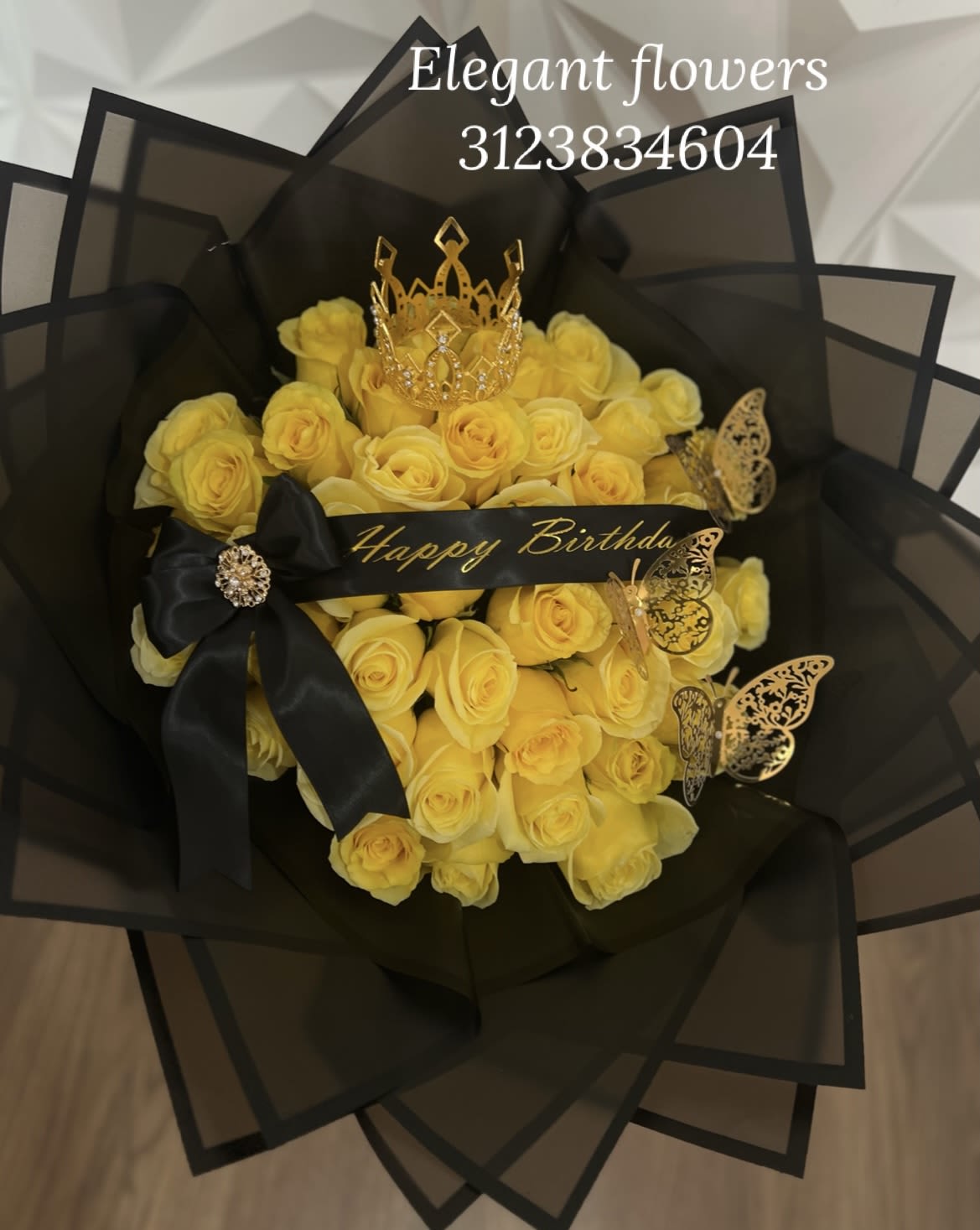 Royal Bloom Bouquet - A stunning bouquet featuring 50 yellow roses, adorned with a golden crown, a personalized ribbon, and decorative golden butterflies, all elegantly wrapped in black Korean-style paper. This luxurious arrangement blends bold sophistication with radiant beauty, making it a perfect statement piece for birthdays, celebrations, or any unforgettable special occasion.