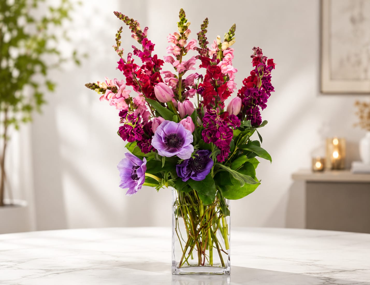 Lavender Garden Elegance - Much like the stunning variety of amethysts in their beautiful shades of purple, this exquisite arrangement showcases the same captivating hues. With the grace of anemones, the charm of tulips, and the whimsy of snapdragons, this bouquet is a visual delight.  It's an ideal February birthday present, capturing the essence of this amethyst-rich month, or a wonderful choice for congratulating someone on their achievements and milestones. Just like the gemstone, this arrangement symbolizes uniqueness and beauty, making it a truly memorable and thoughtful gift.   Approximate Dimensions: 20"D x 27"H