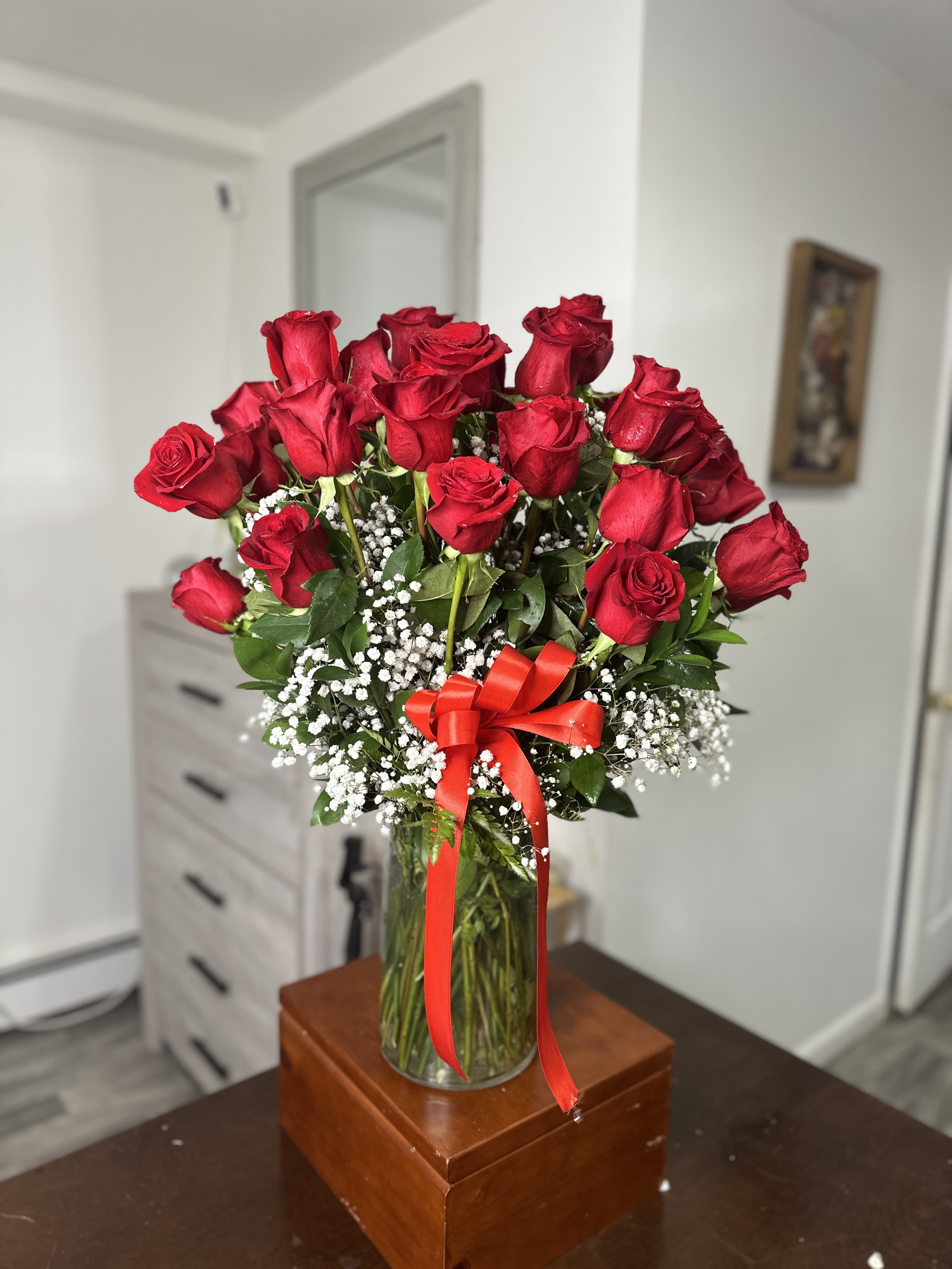 Bouquet of red roses in a glass vase with a red ribbon