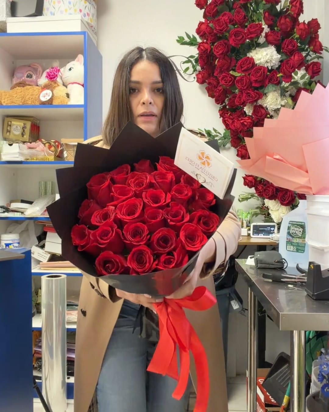 Woman holding a bouquet of red roses wrapped in black paper with a red ribbon