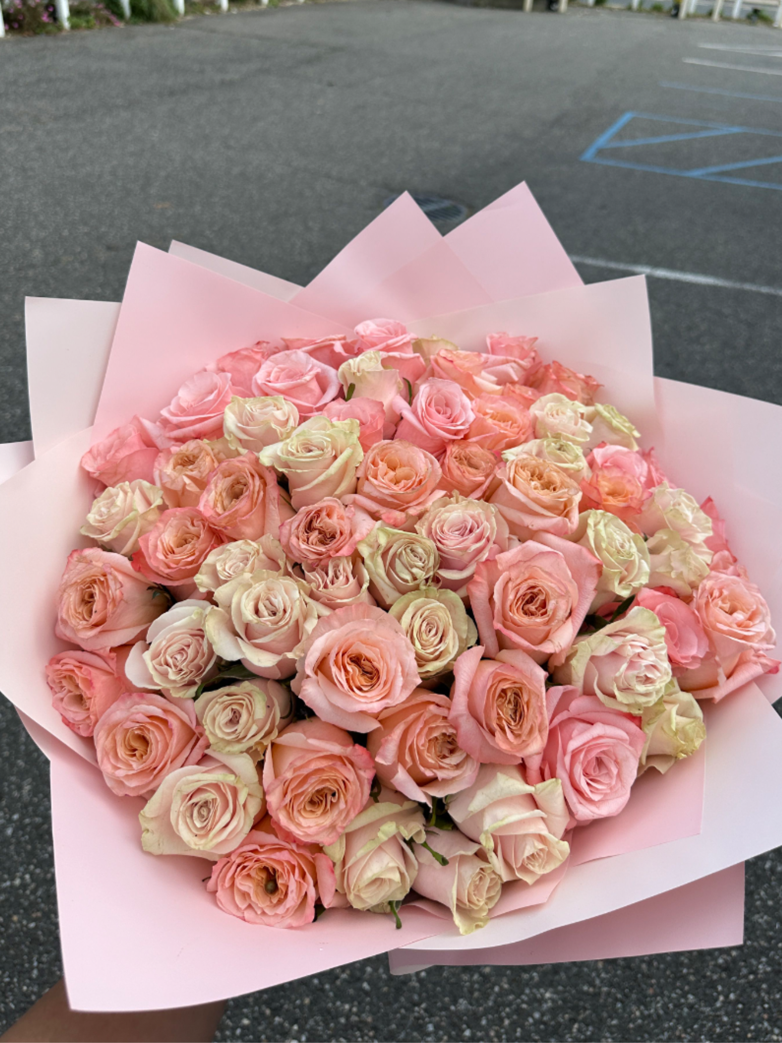 Large bouquet of pale pink and peach roses wrapped in pink paper