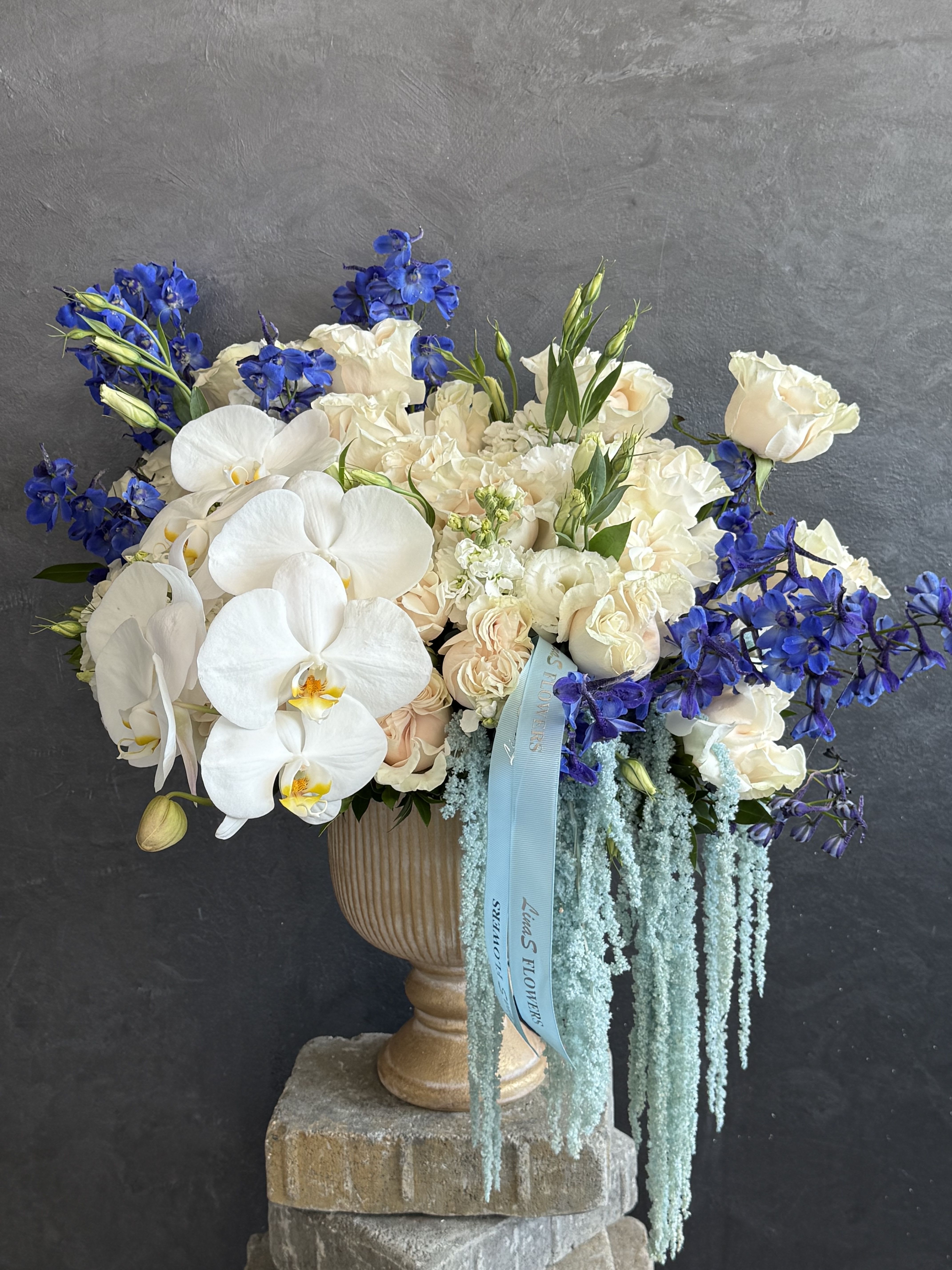Areg - Soft white roses and airy blue delphinium, whispering calm, grace, and refined beauty