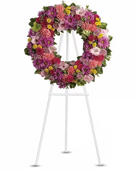 Ringed by Love - The memory of brighter days is always a comfort to those in mourning. This lovely wreath will display your compassion beautifully. A standing wreath of dazzling flowers such as green hydrangea, hot pink spray roses, pink gladioli and carnations along with a mélange of multi-colored daisy spray and cushion spray chrysanthemums and greenery is delivered on an easel. 