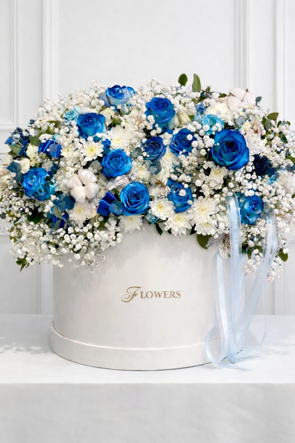 Blue and white rose arrangement in a round white box with ribbon