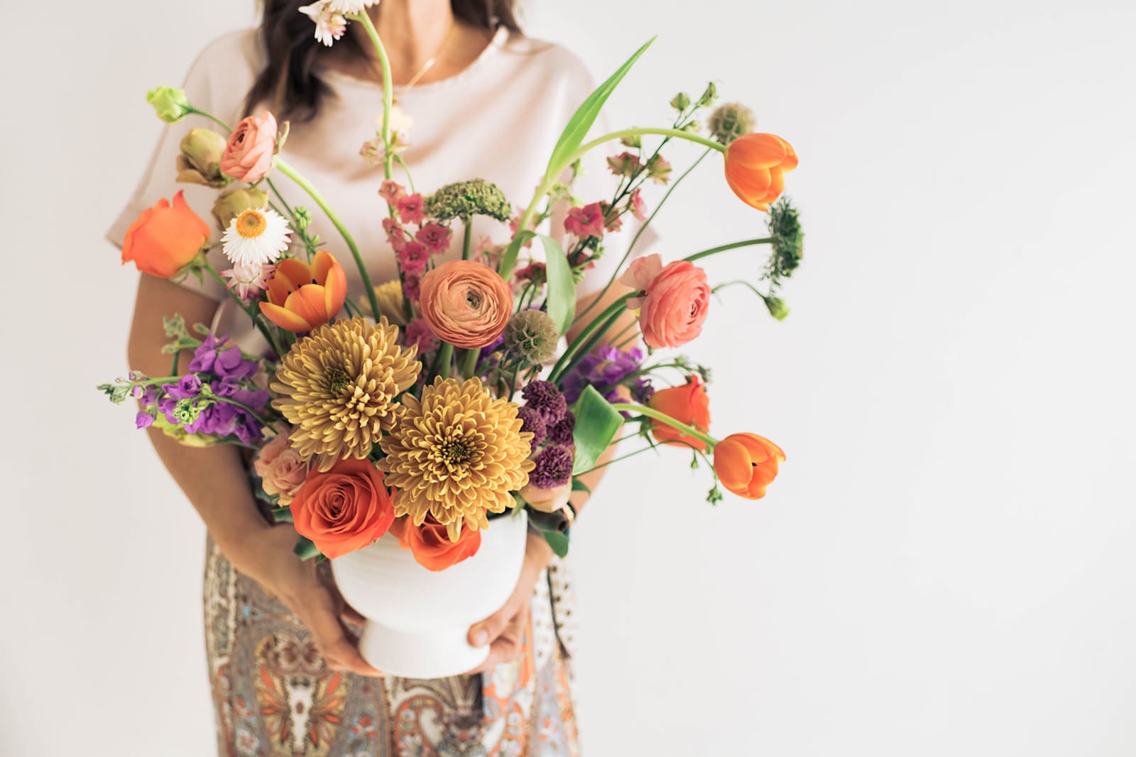 Mixed bouquet in a white vase with orange, pink, purple, and yellow flowers