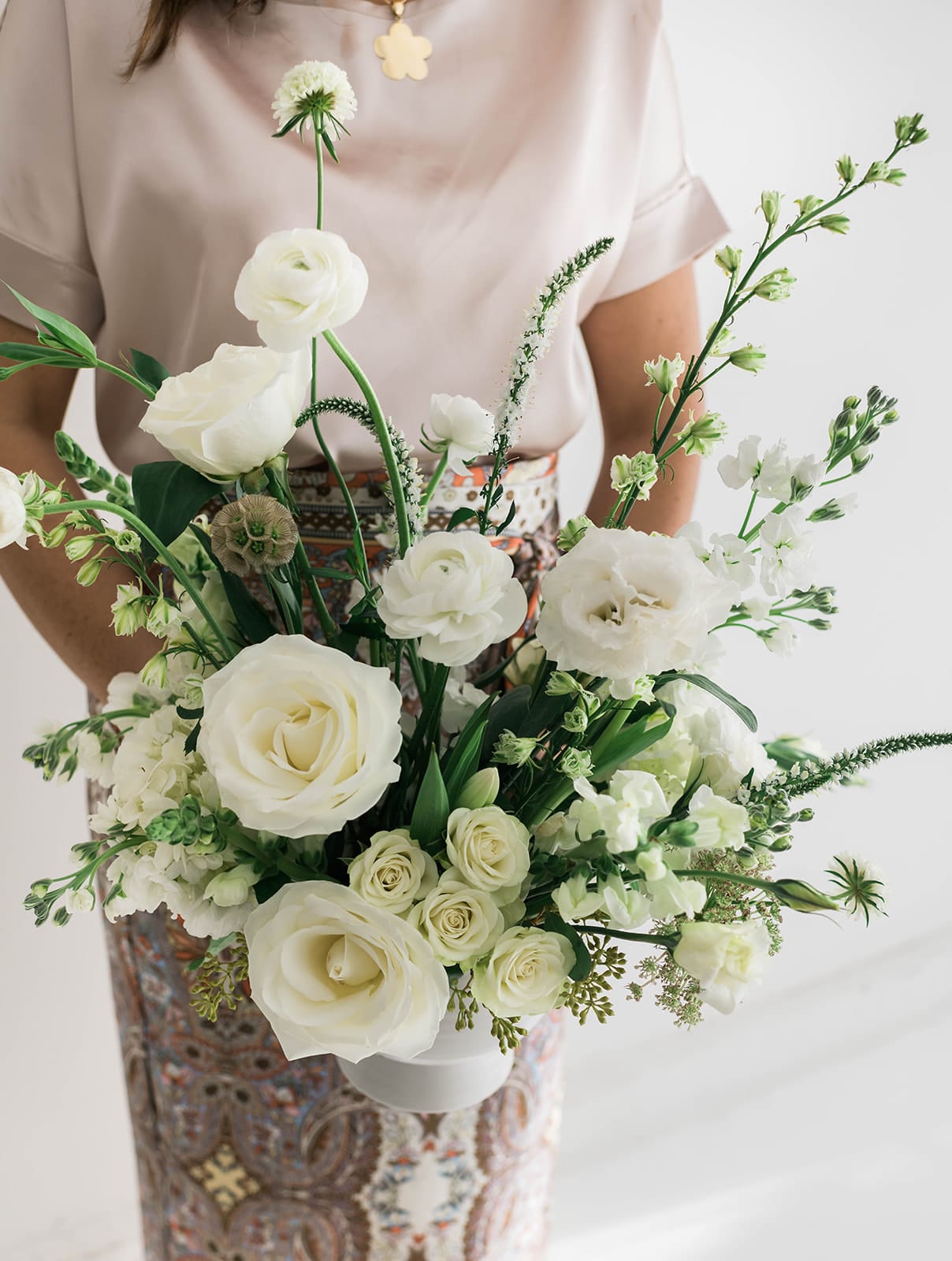 Woman holding a white bouquet of roses and mixed blooms