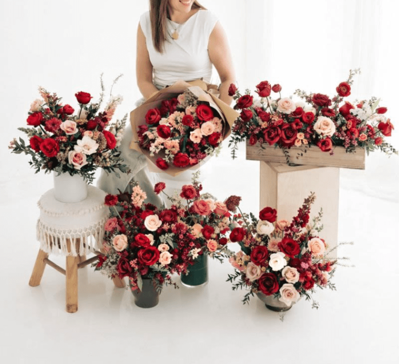 Assorted red and blush rose arrangements with a woman holding a bouquet