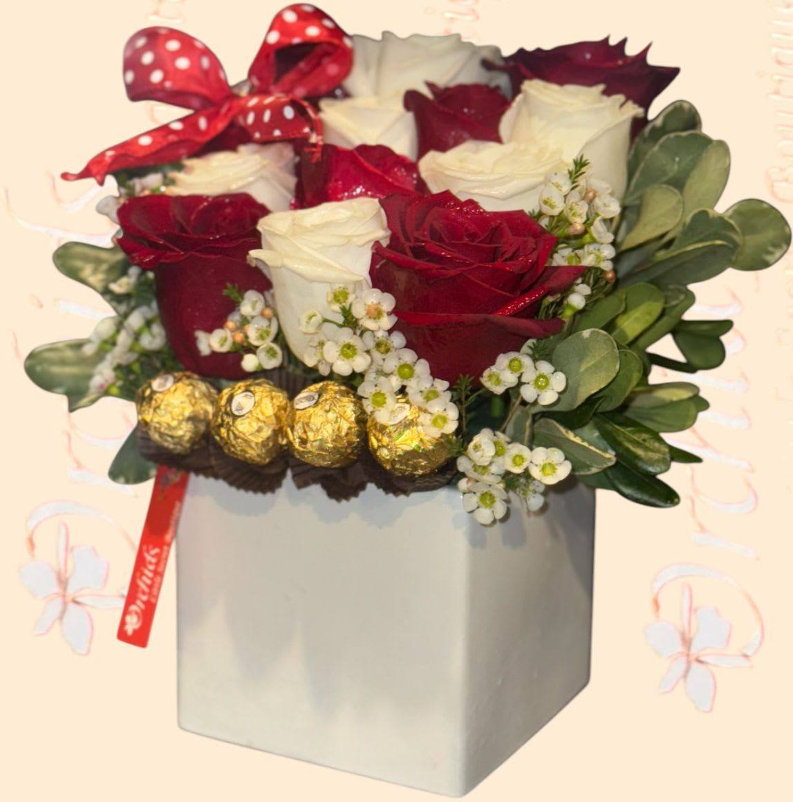 Red and white roses in a gray box with a polka-dot bow and chocolates