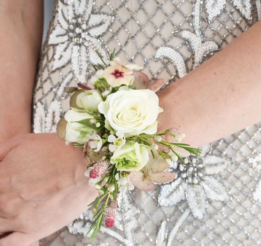 Wrist corsage of white roses and small pink flowers on a beaded dress.