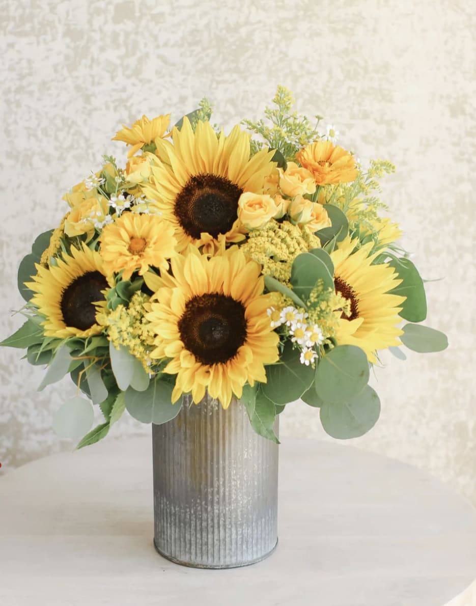 Yellow sunflower and rose arrangement in a tall galvanized metal vase