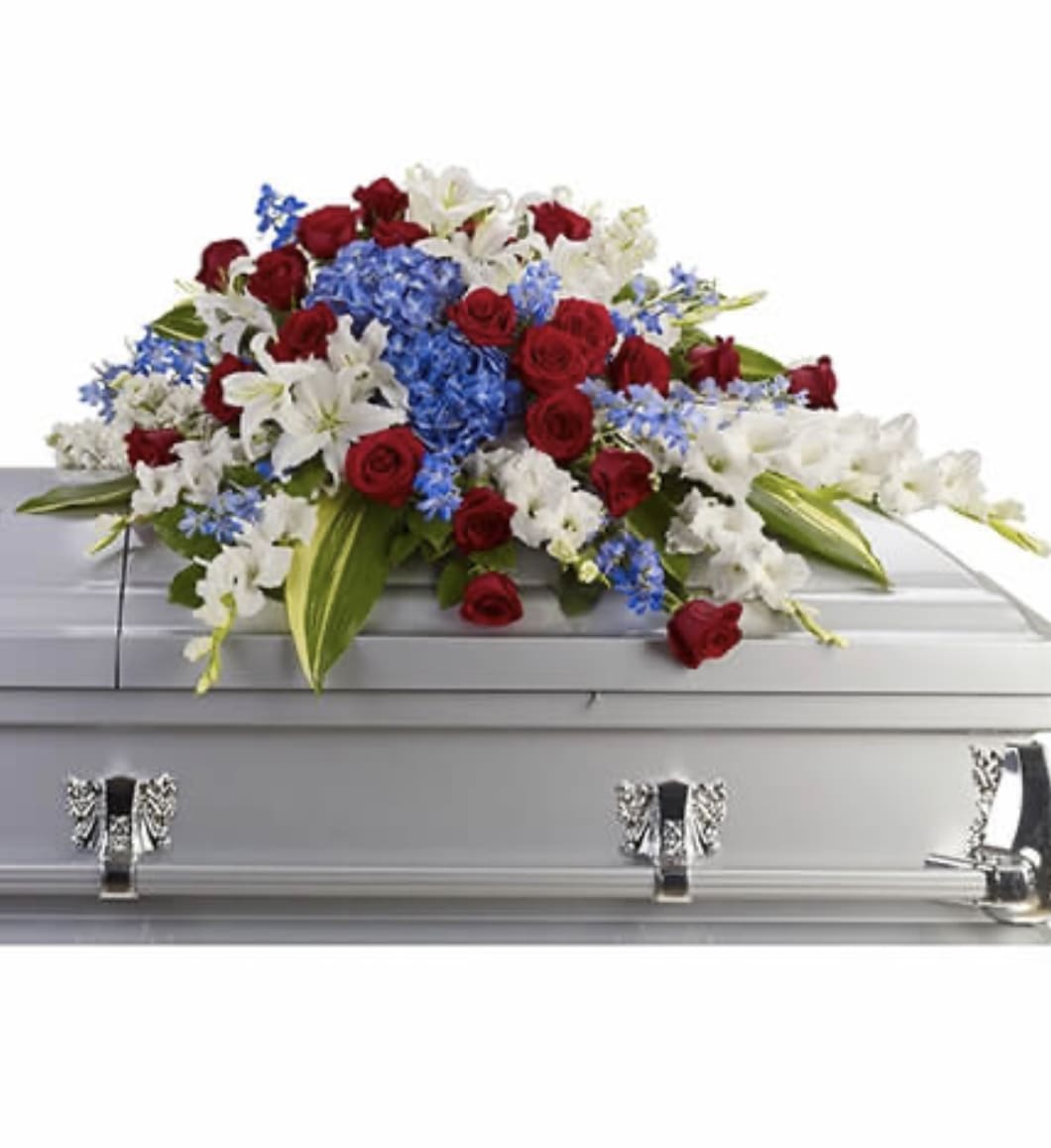 Red, white, and blue casket spray with roses, lilies, and delphinium on a silver casket
