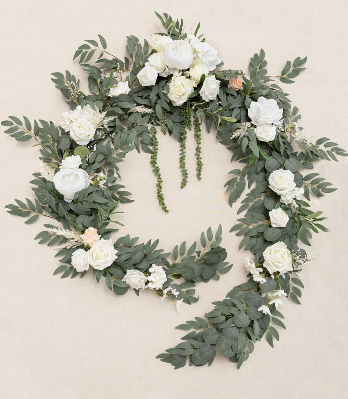 Large open wreath of cascading greenery with white roses and peonies and a touch of peach blooms